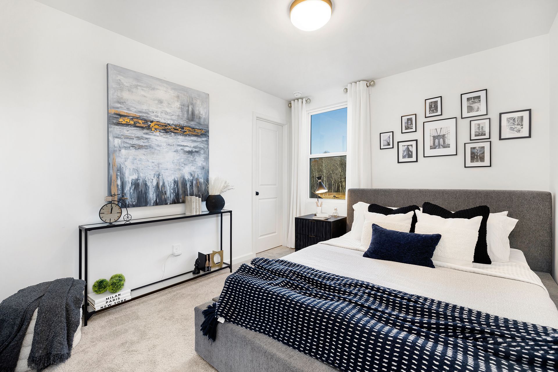 A bedroom with a large bed and a painting on the wall.