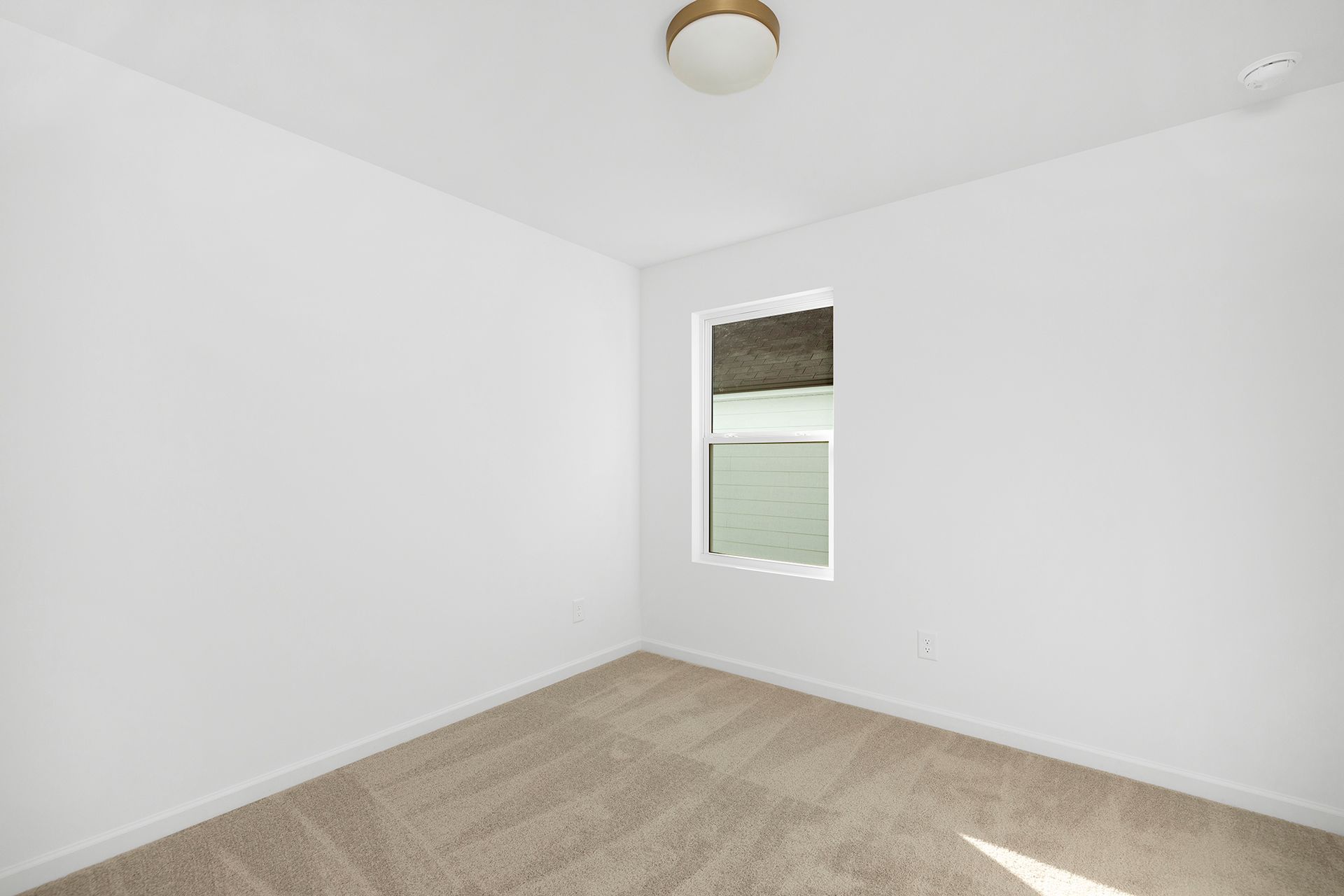 An empty bedroom with a window and a ceiling fan.