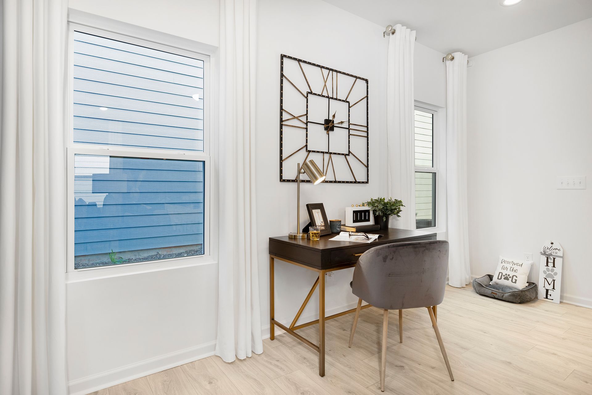 There is a desk and chair in the room with a clock on the wall.