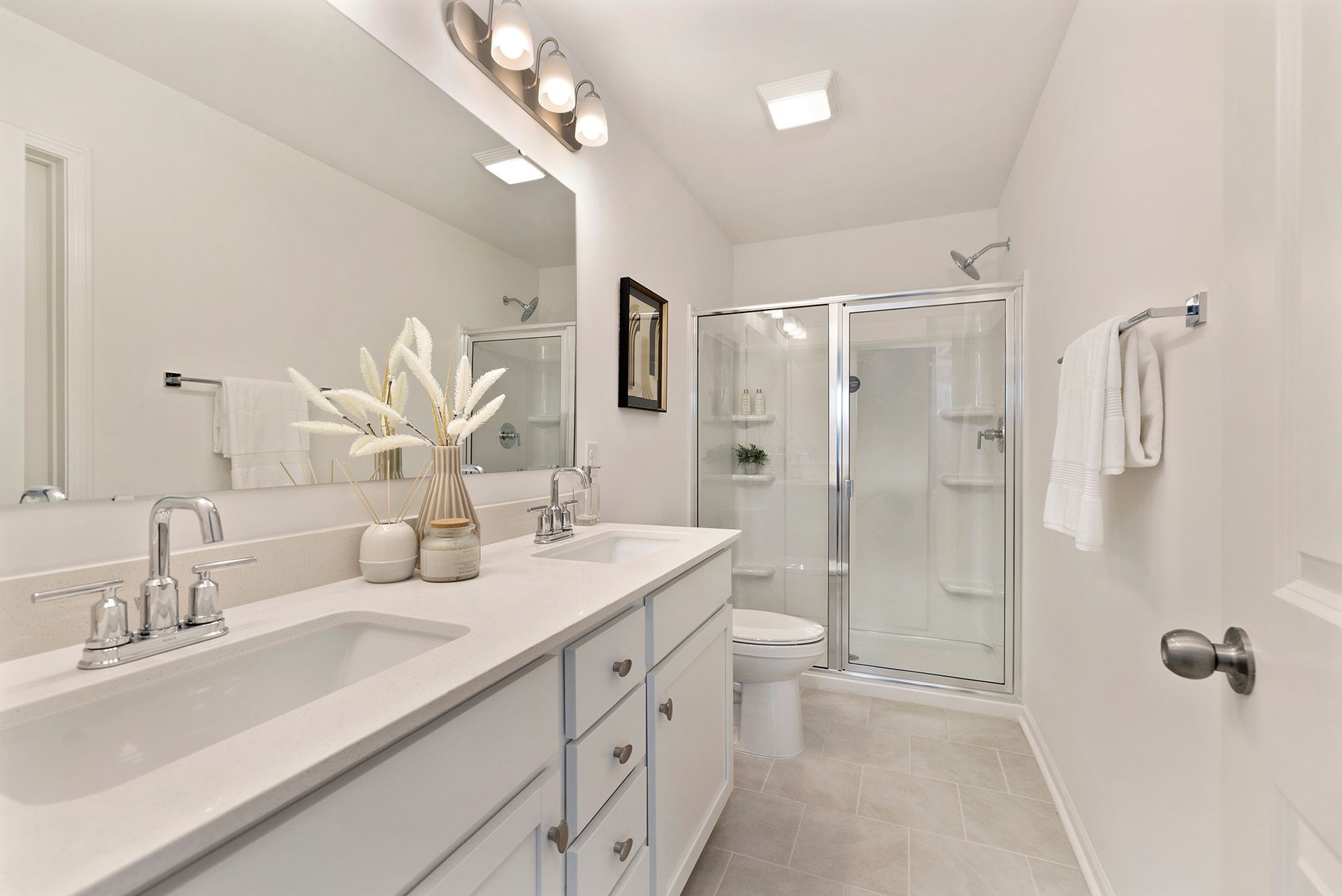 A bathroom with two sinks , a toilet , and a walk in shower.