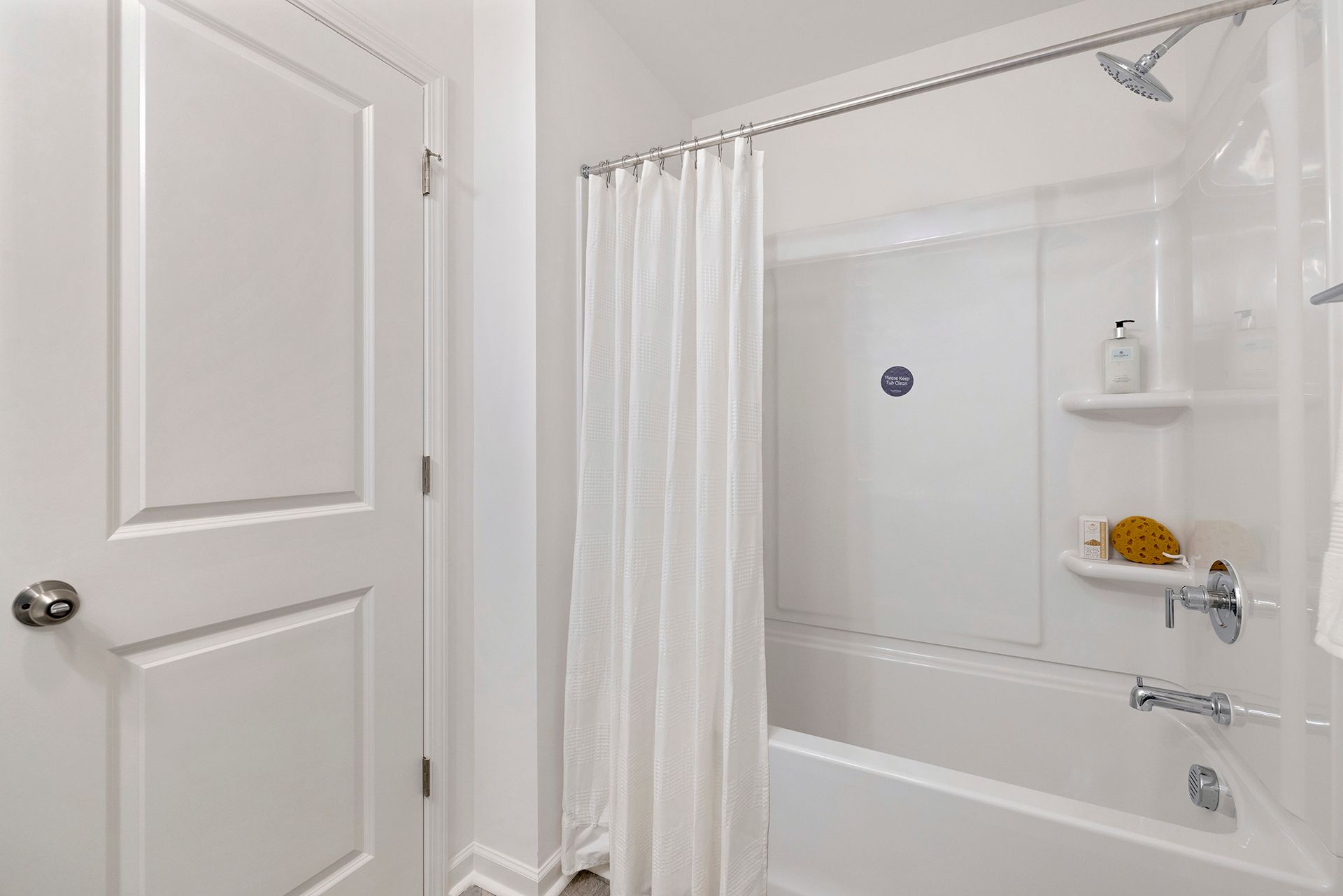 A bathroom with a tub , shower , and door.