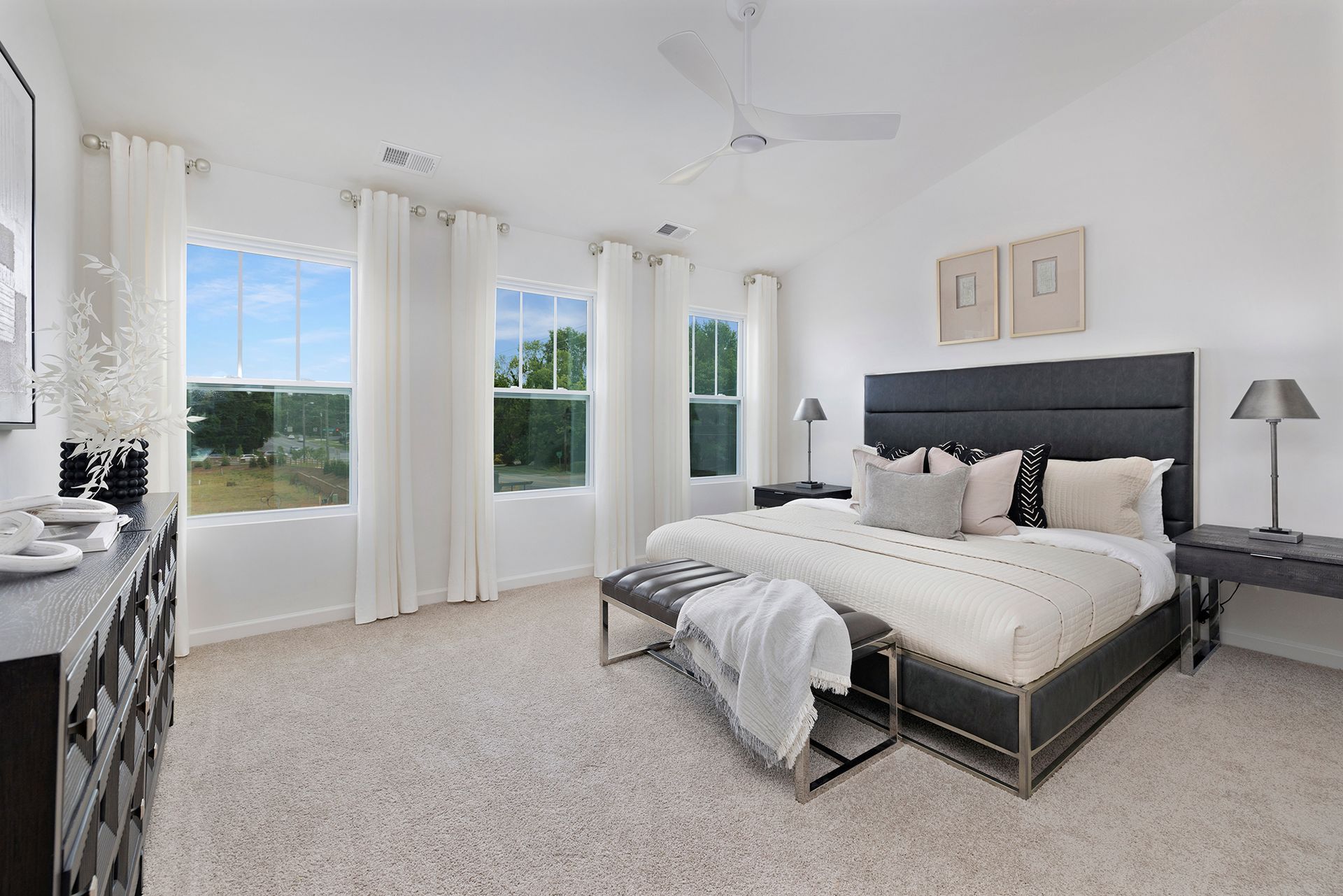 A bedroom with a king size bed , a dresser , and two windows.