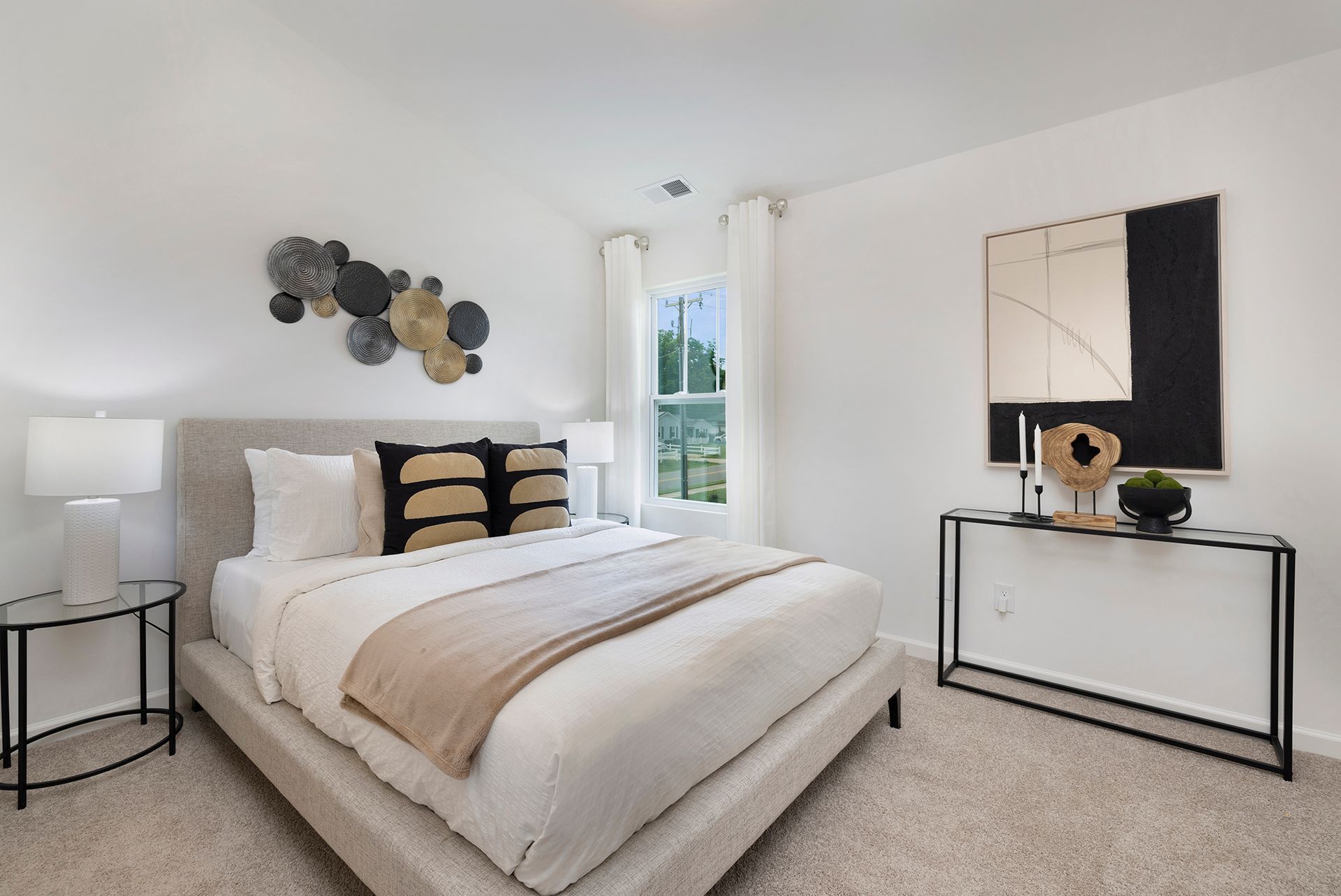 A bedroom with a large bed , nightstands , lamps and a painting on the wall.