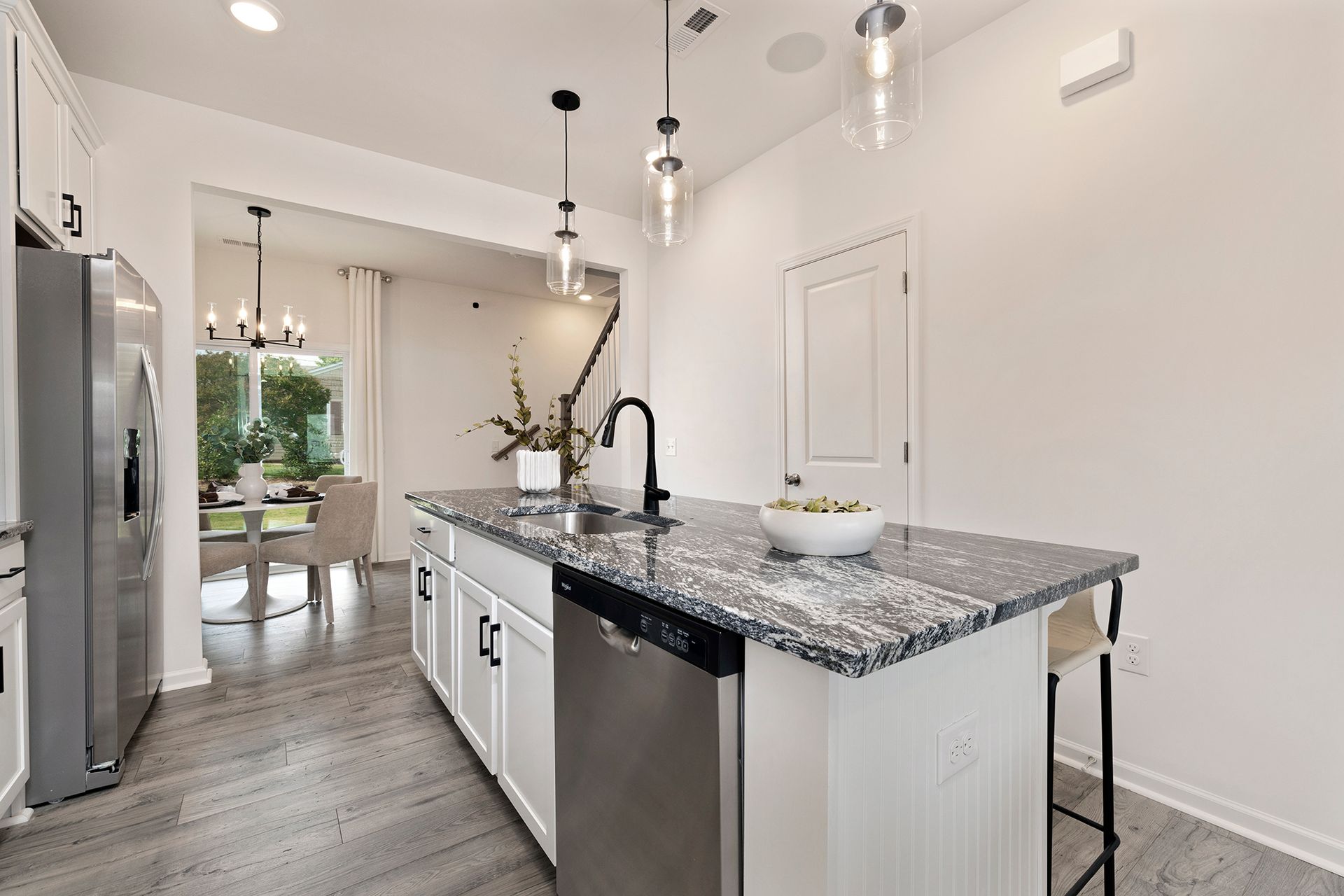 A kitchen with white cabinets , granite counter tops , stainless steel appliances and a large island.