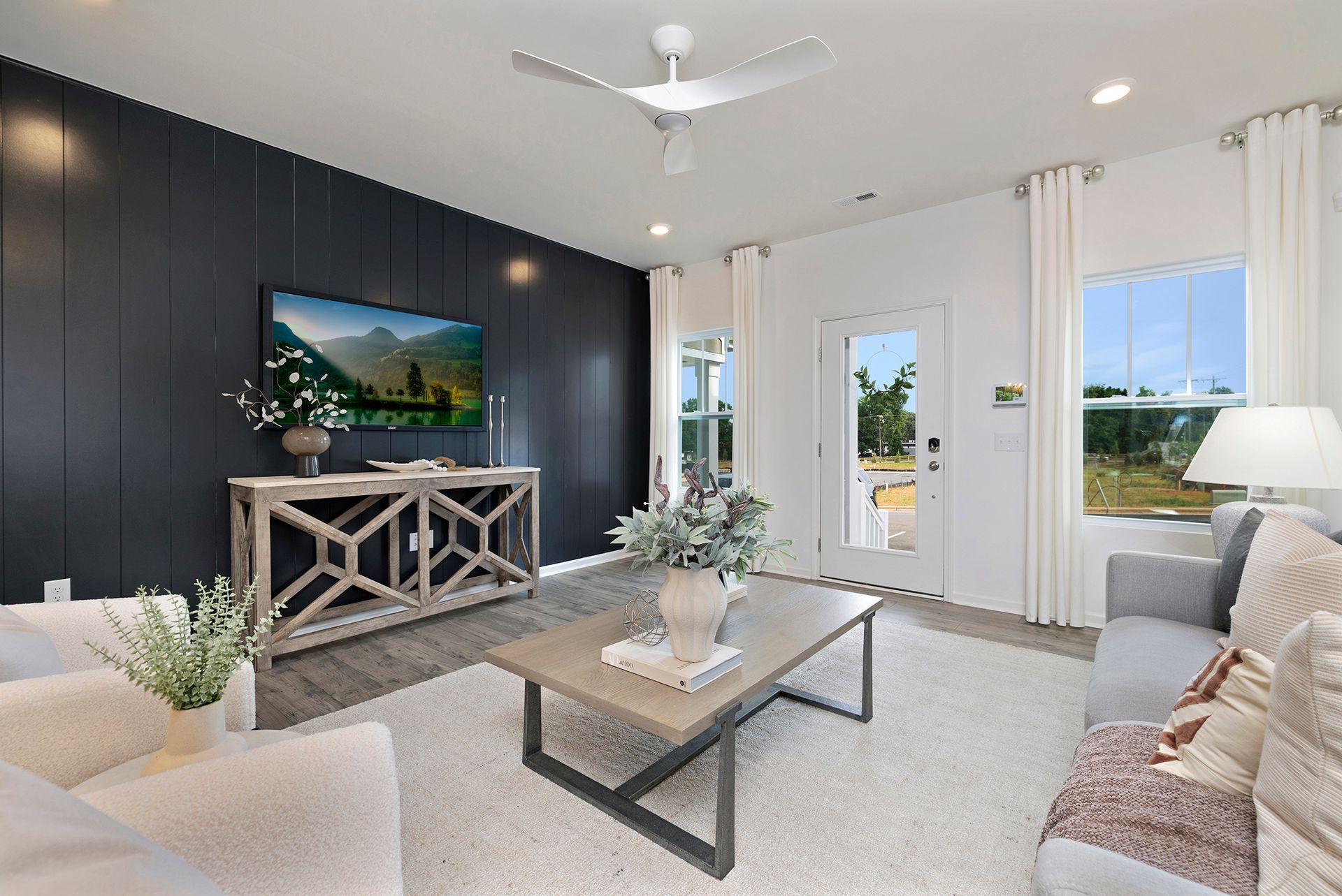 A living room with a ceiling fan and a flat screen tv