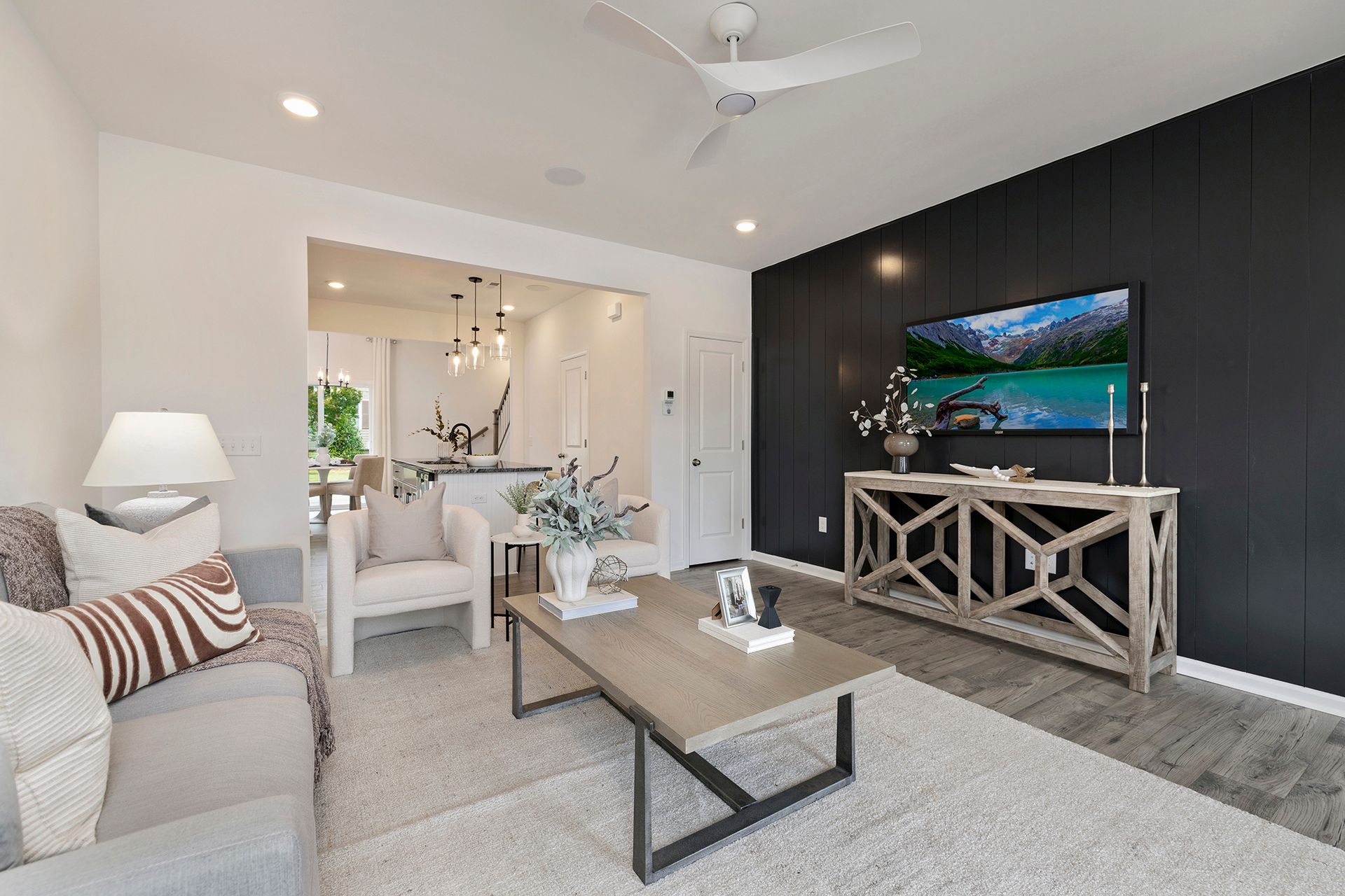 A living room with a couch , coffee table , television and ceiling fan.