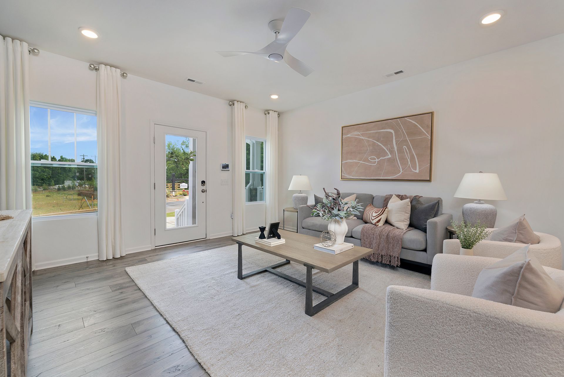 A living room with a couch , chairs , coffee table and a ceiling fan.