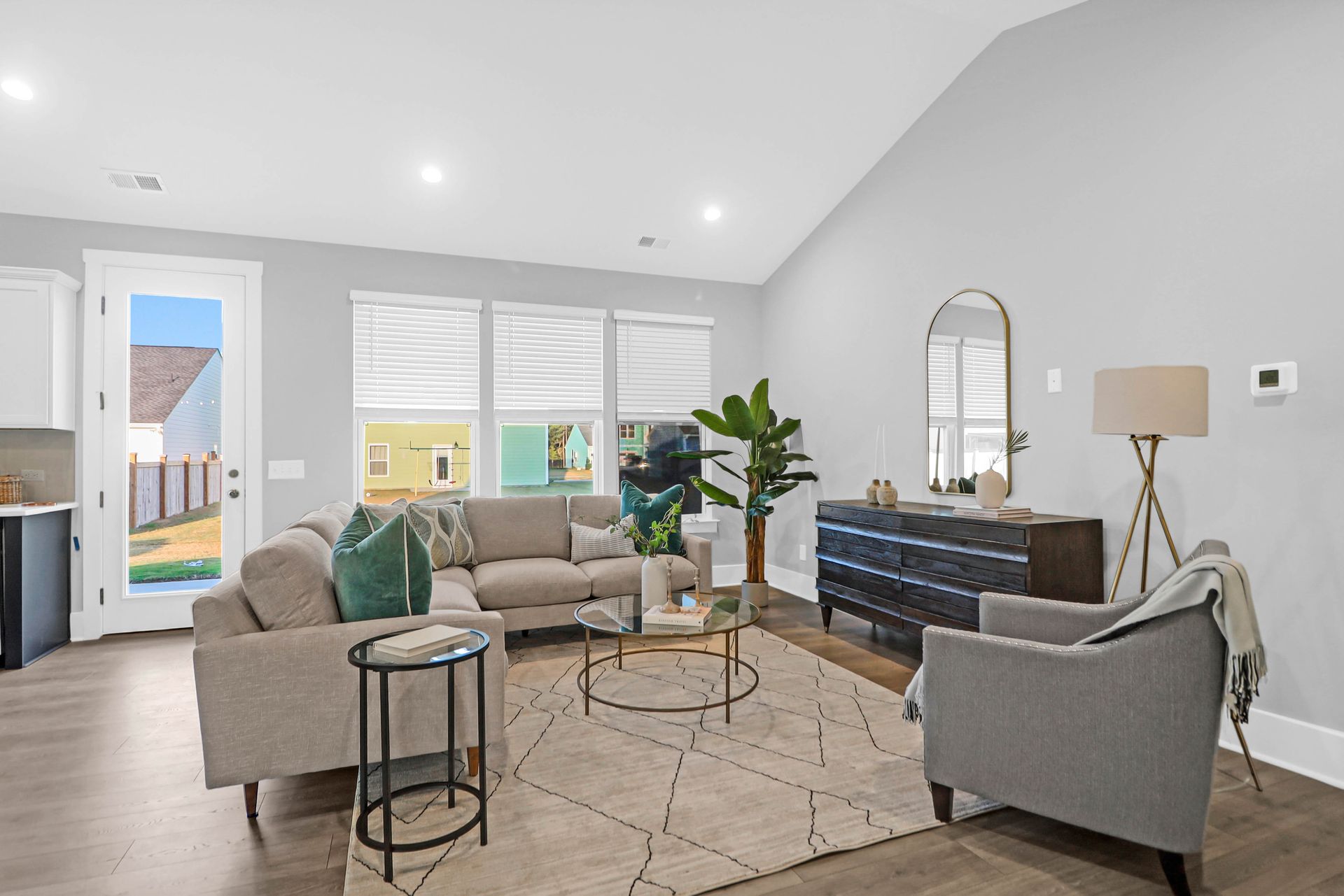 A living room with a couch , two chairs , a table and a mirror.
