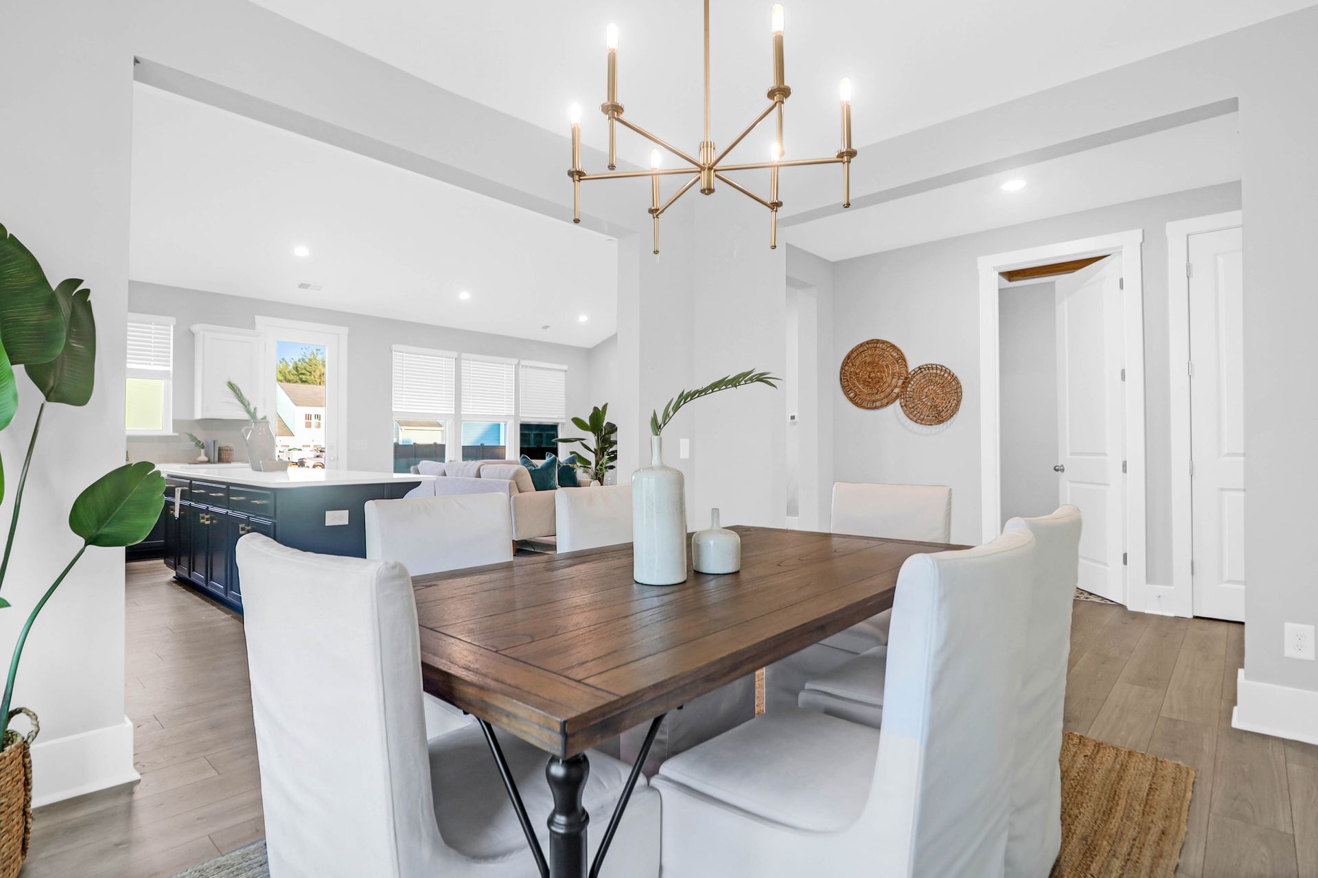 A dining room with a wooden table and white chairs and a chandelier.