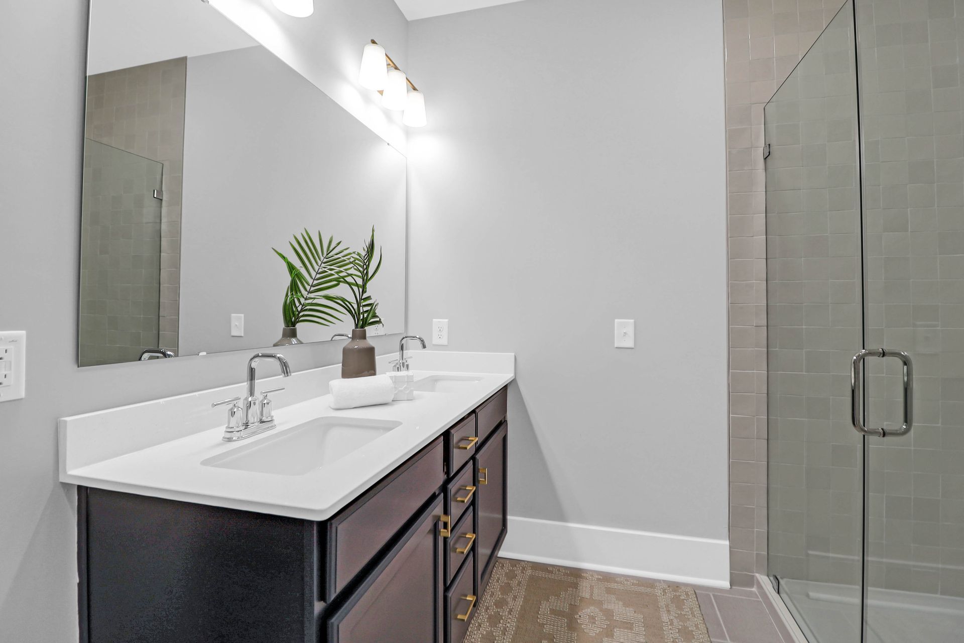 A bathroom with two sinks and a walk in shower.