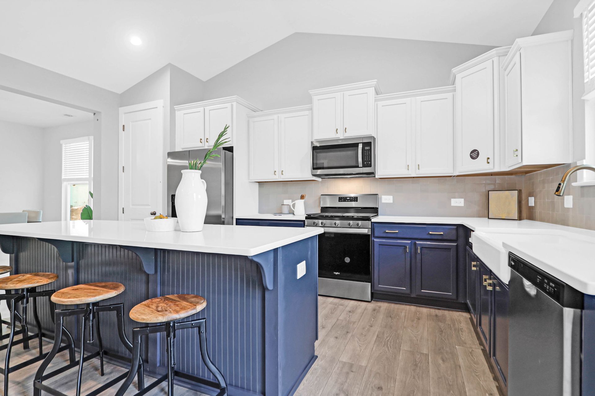 A kitchen with blue cabinets , white cabinets , stainless steel appliances and a large island.