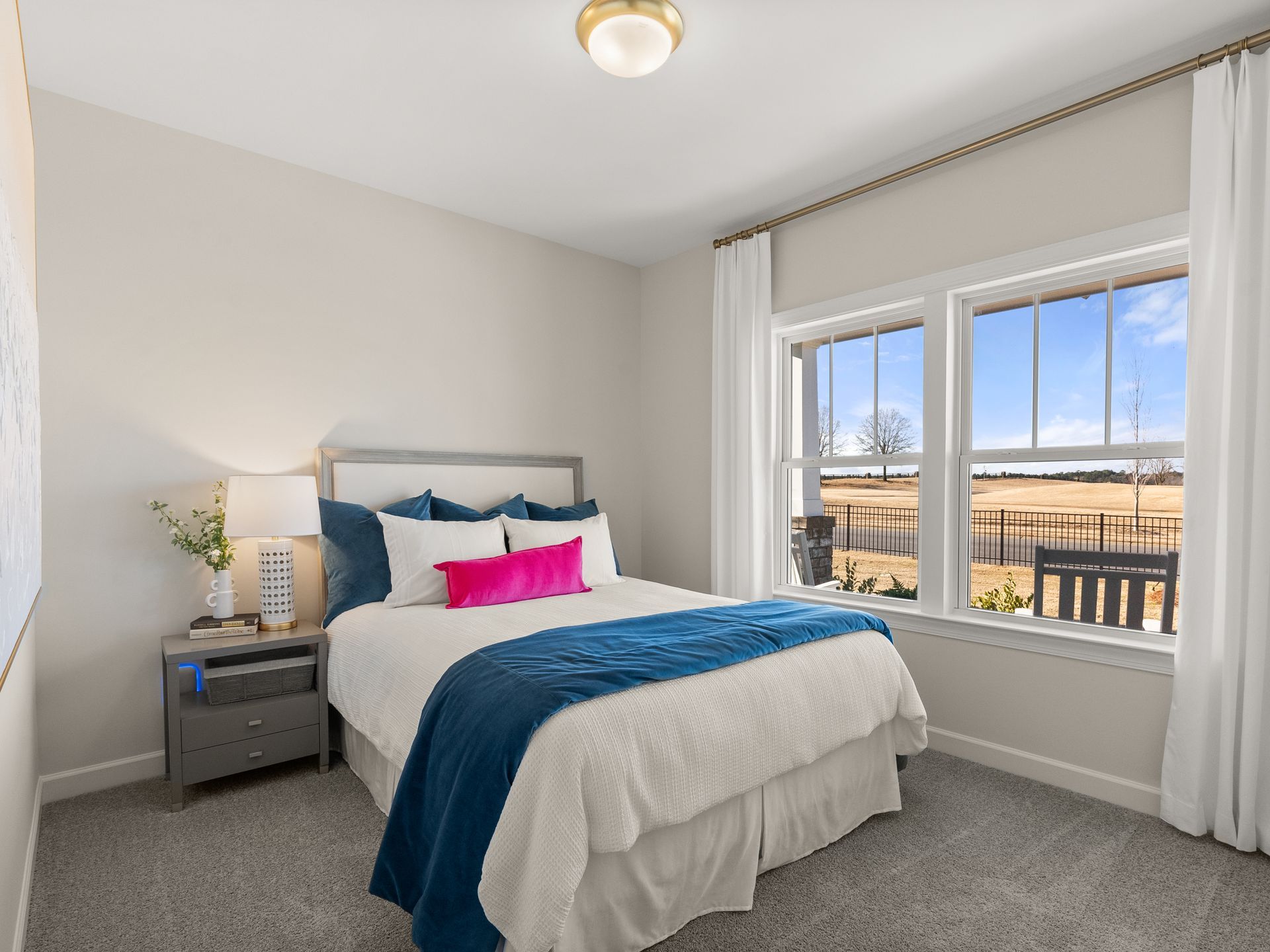 A bedroom with a bed , nightstand , and two windows.