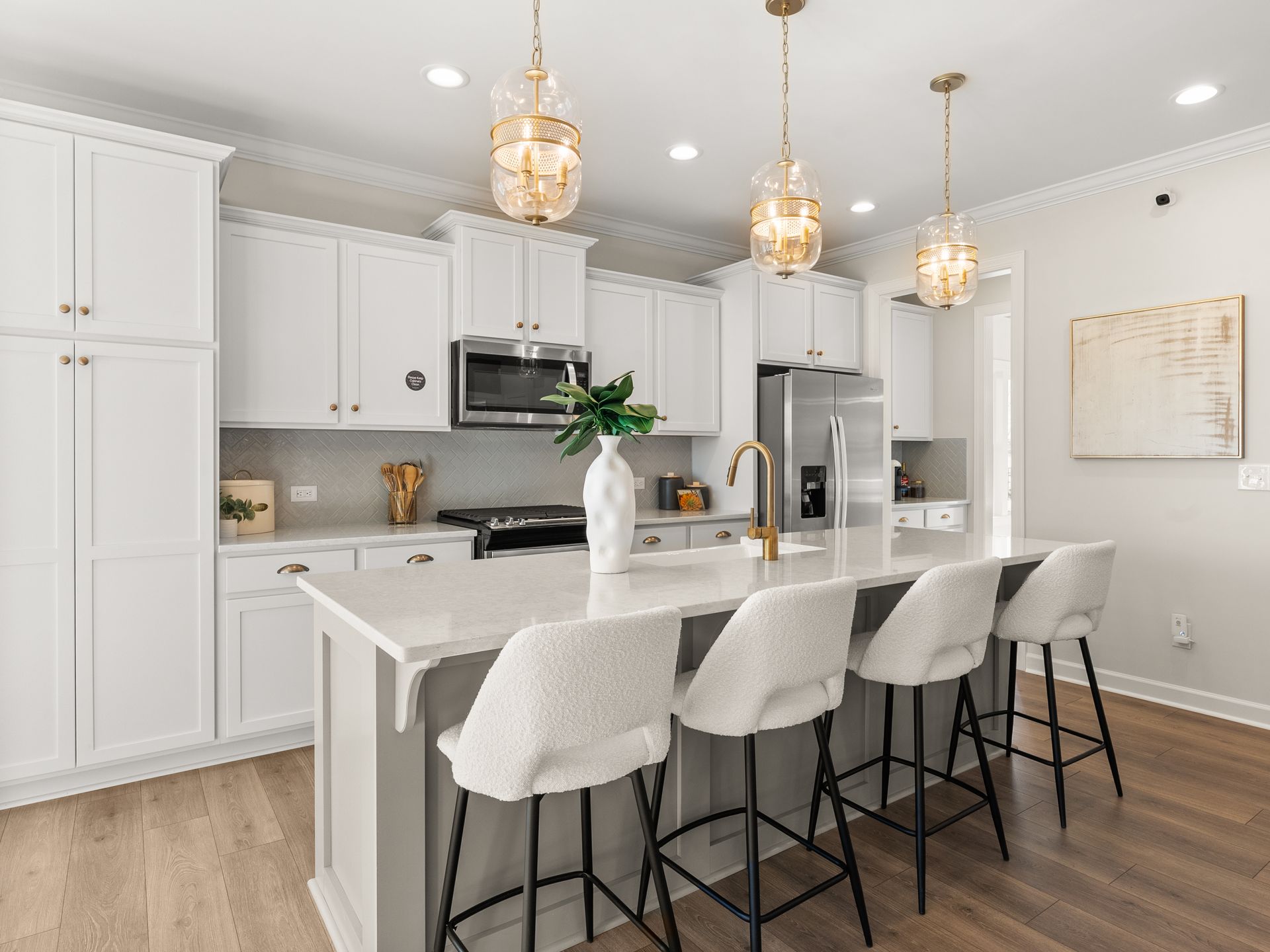 A kitchen with white cabinets , a large island , and stools.