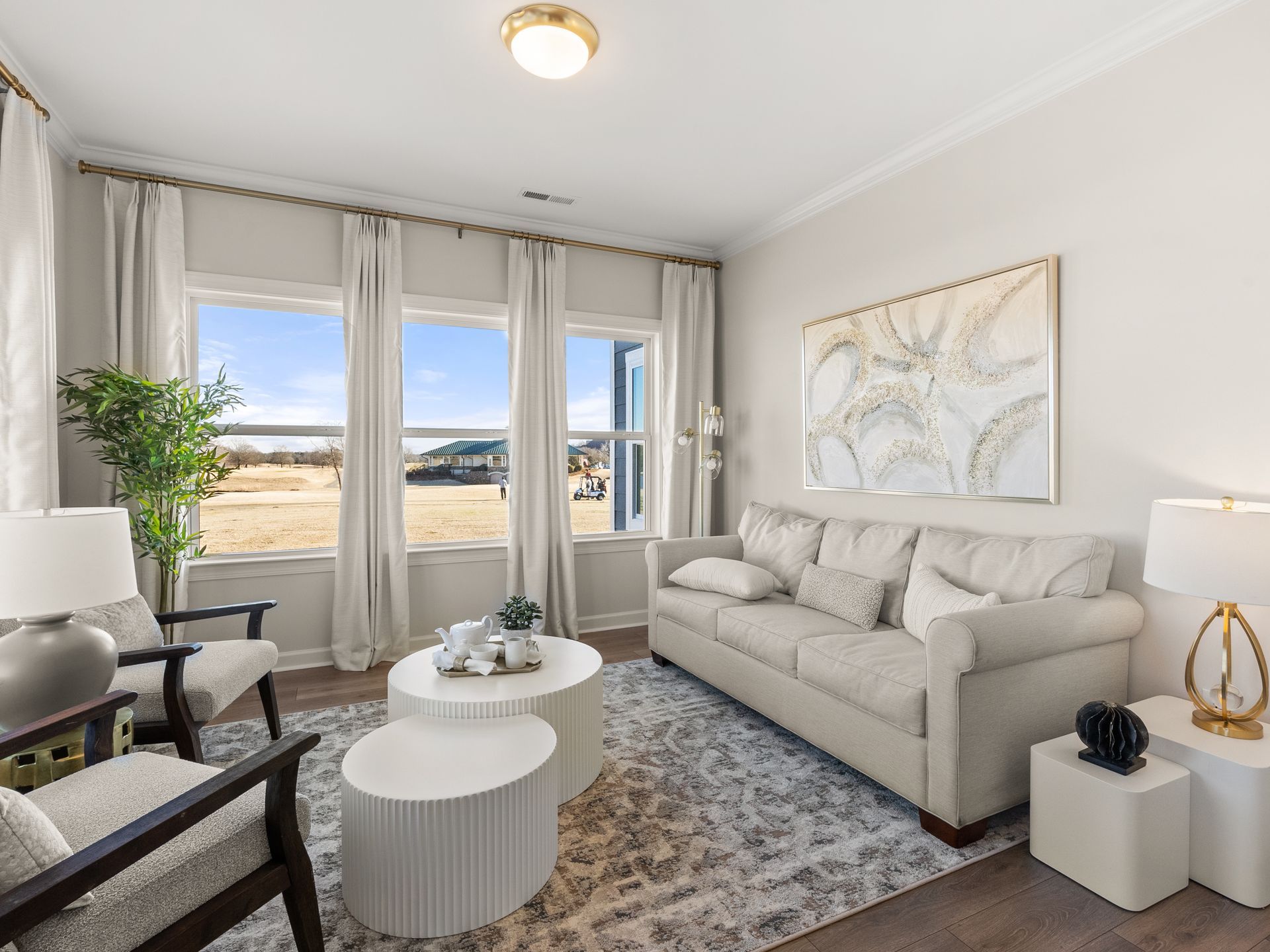 A living room with a couch , chairs , tables and windows.