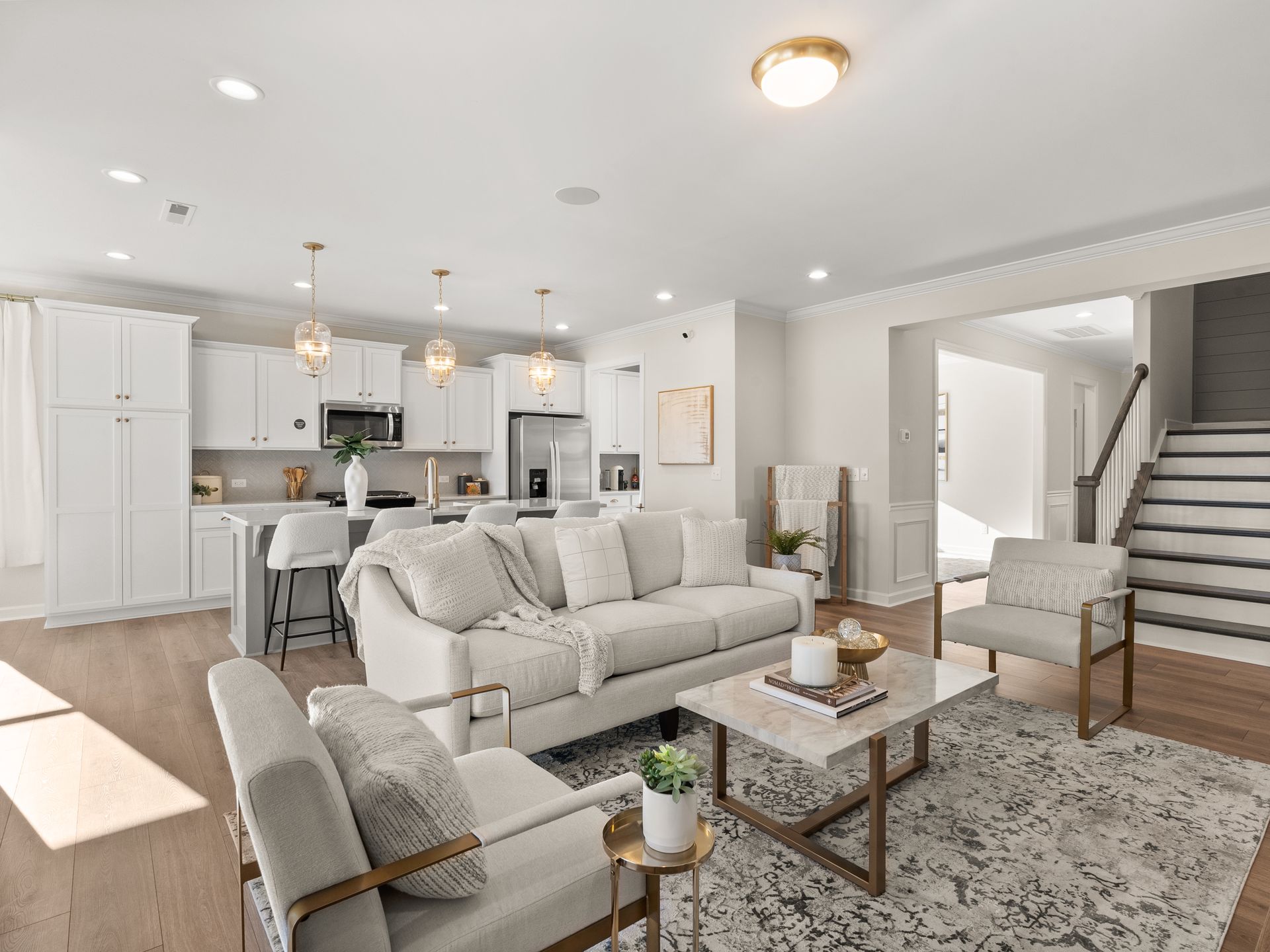 A living room with a couch , chairs , coffee table and stairs.