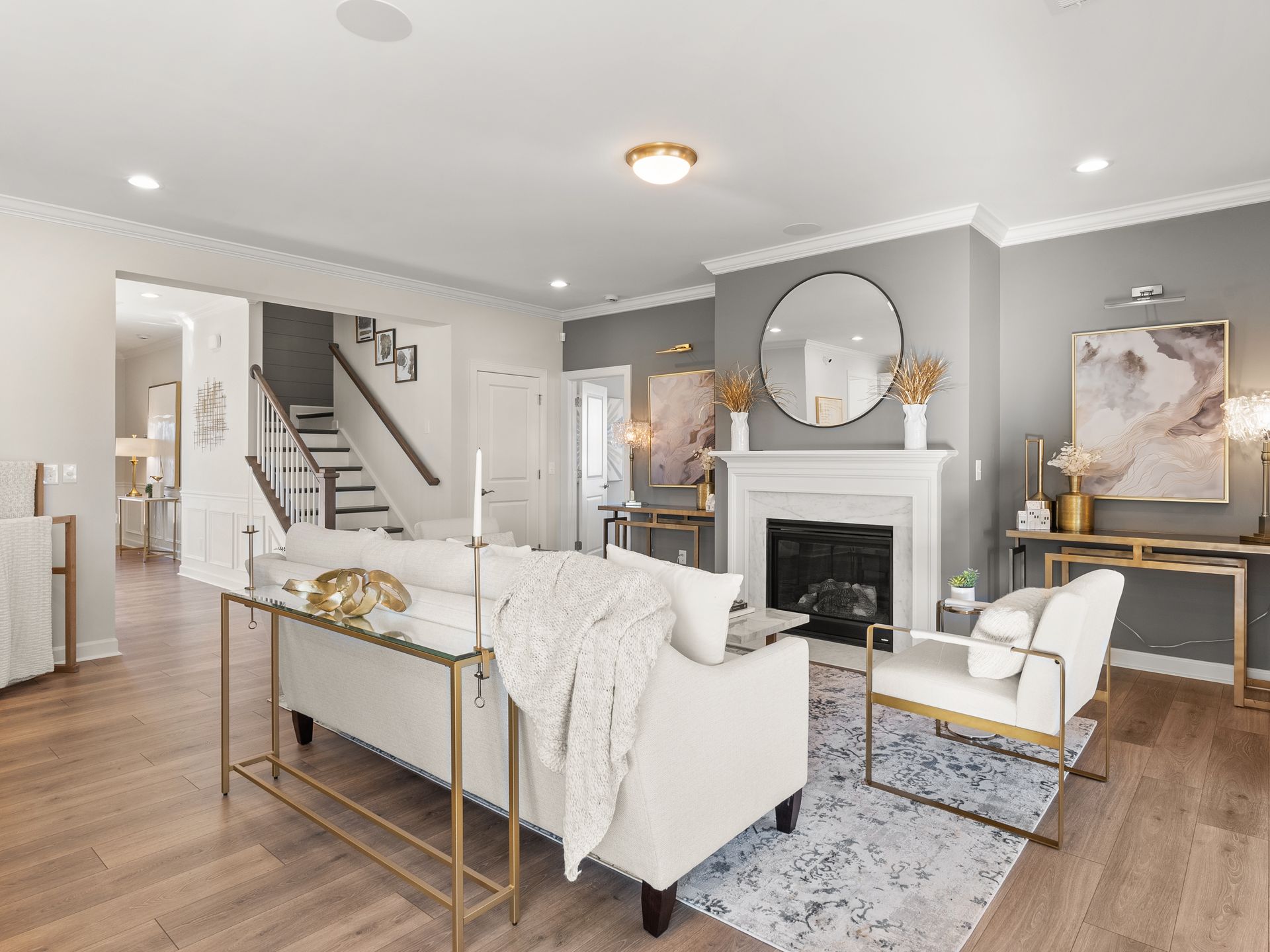 A living room with a couch , chairs , fireplace and stairs.
