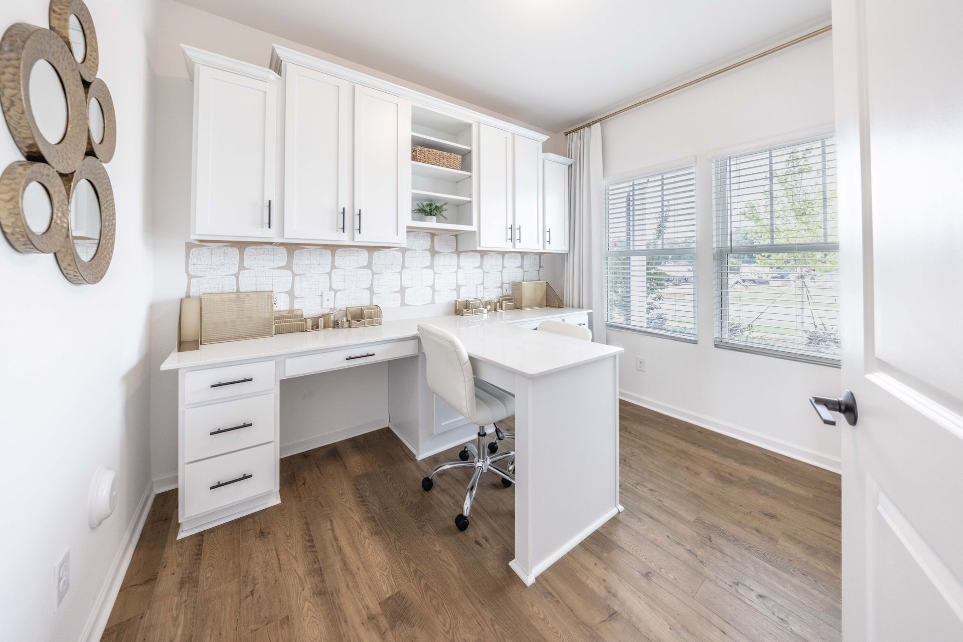 A home office with white cabinets , a desk and a chair.