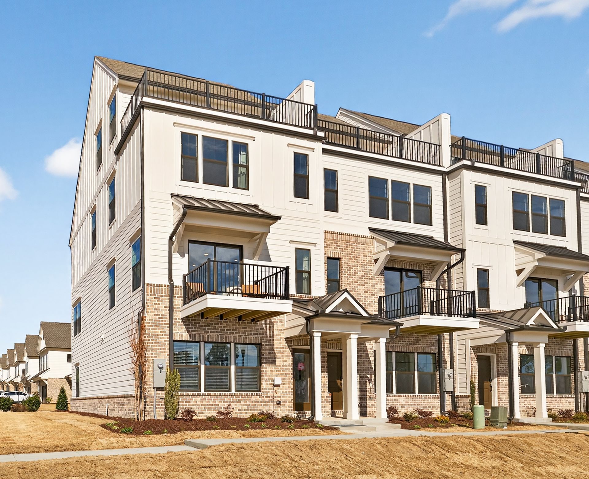 Aerial view of a residential development nestled in a wooded area, with construction in foreground and blue sky.