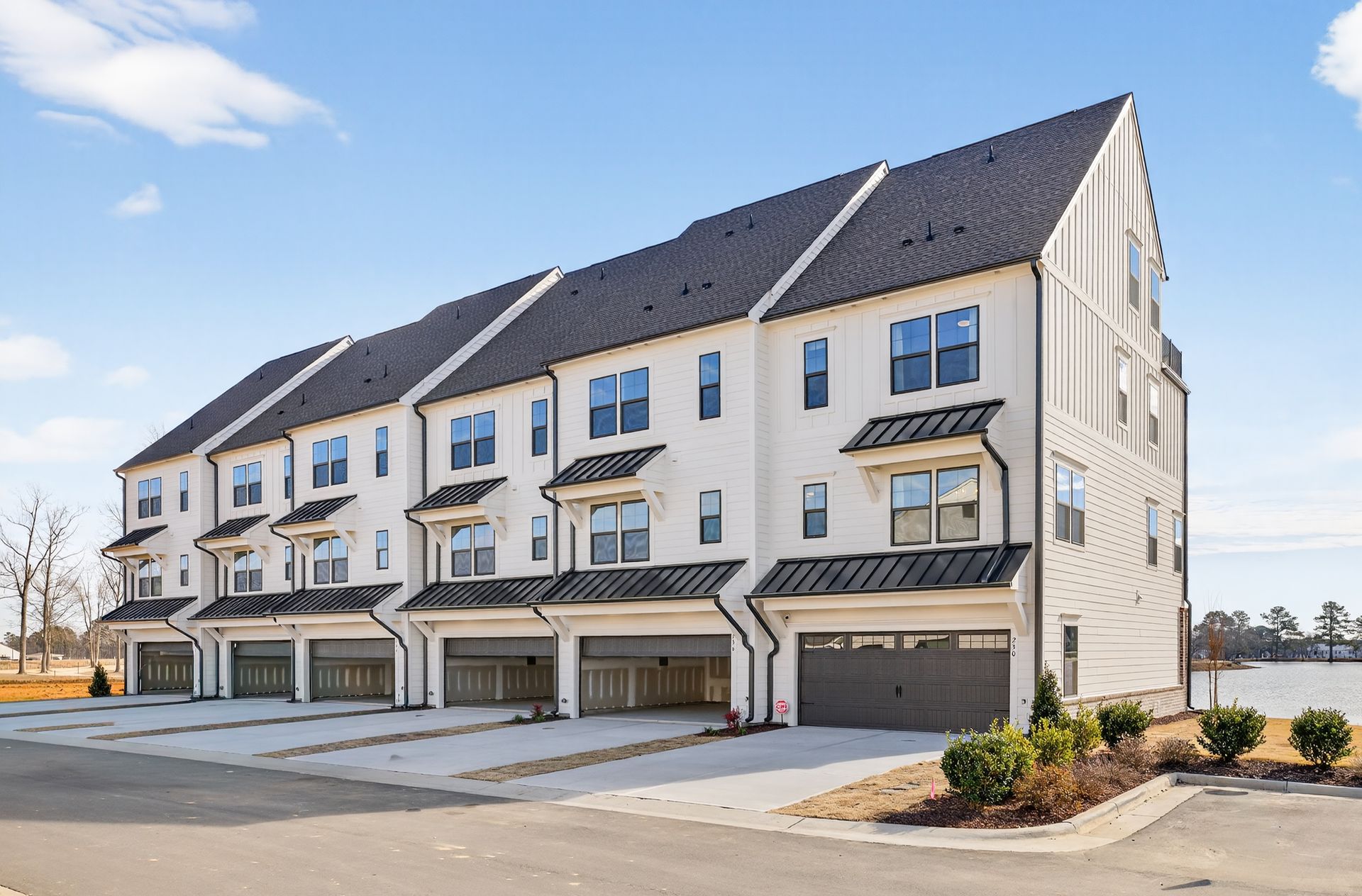 Row of colorful townhouses with cars parked in front; blue sky background.