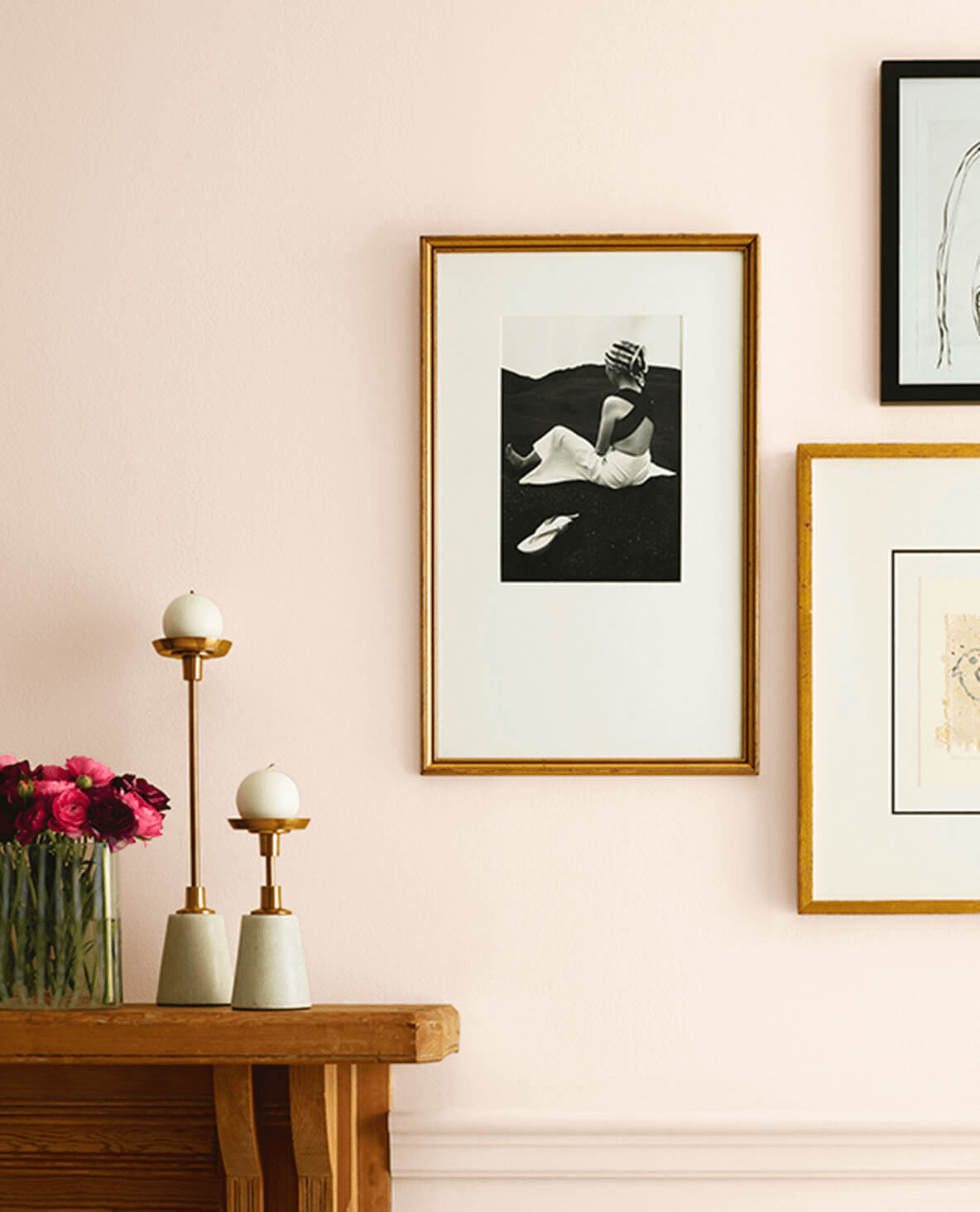 A picture of a woman laying on a bed hangs on a pink wall