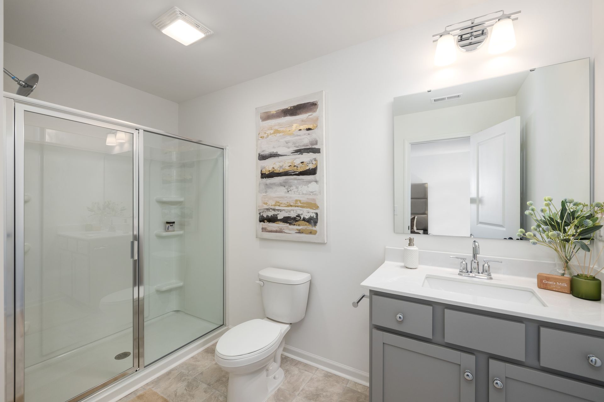 A bathroom with a toilet , sink , shower and mirror.