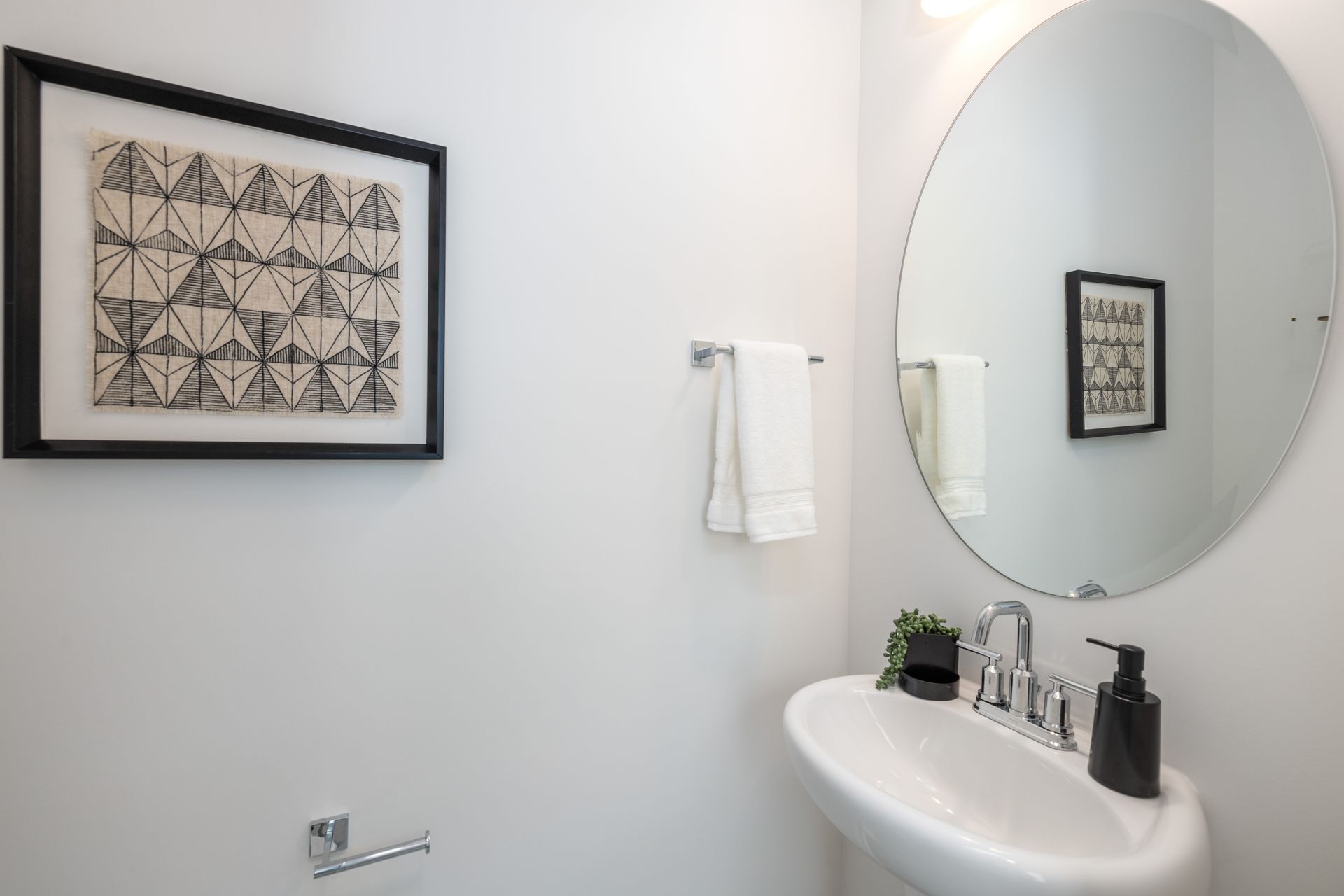 A bathroom with a sink , mirror and picture on the wall.