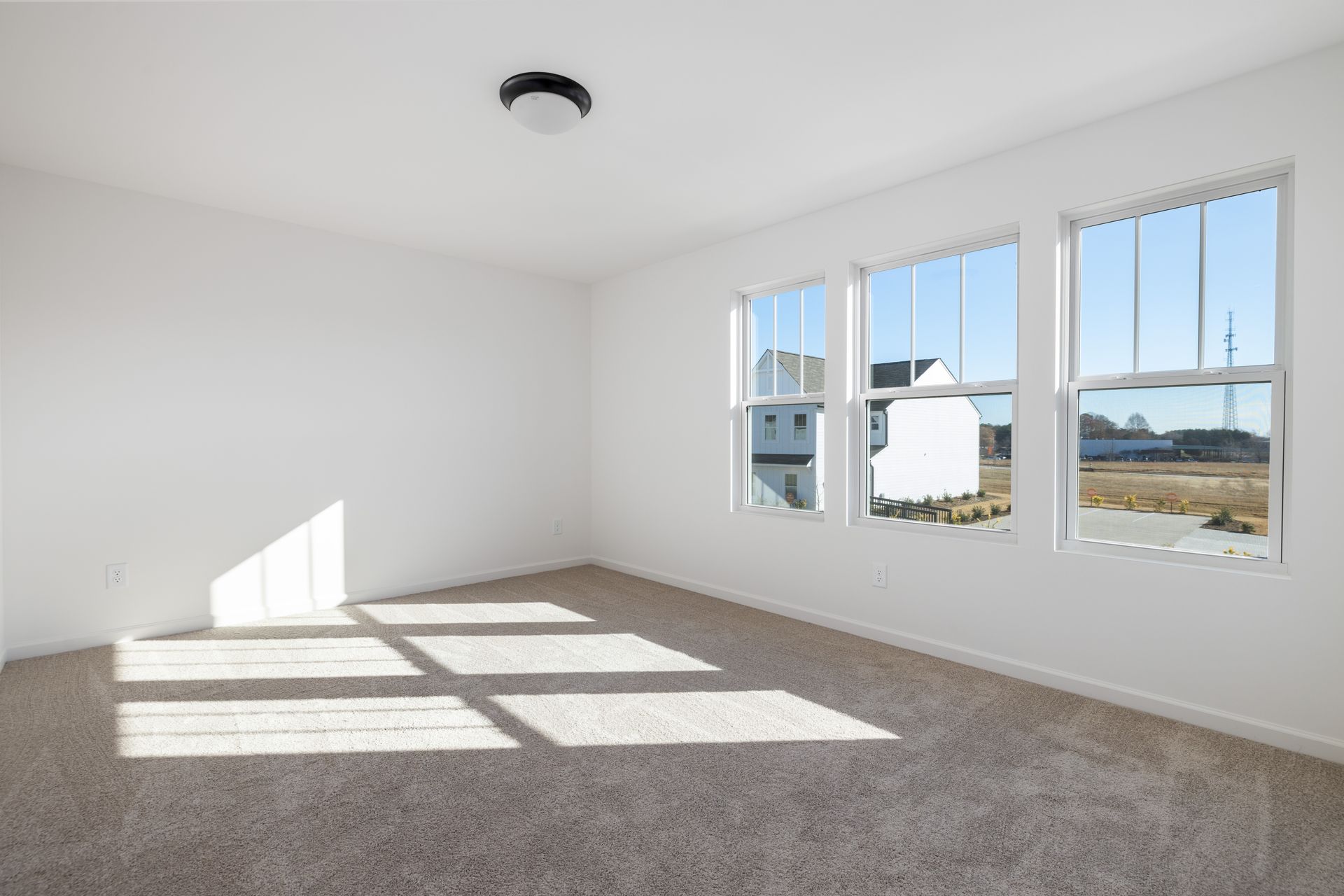 An empty room with a lot of windows and a ceiling light.