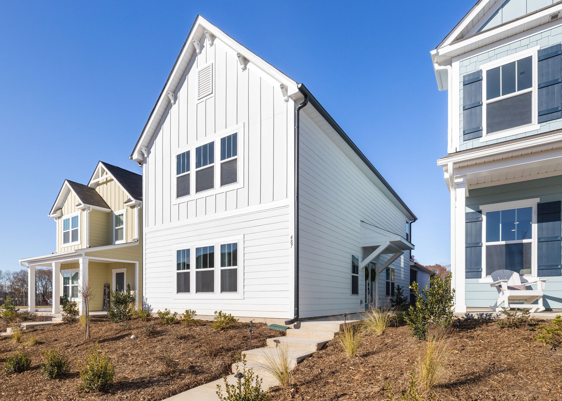 A white house with a lot of windows is sitting on top of a dirt hill.