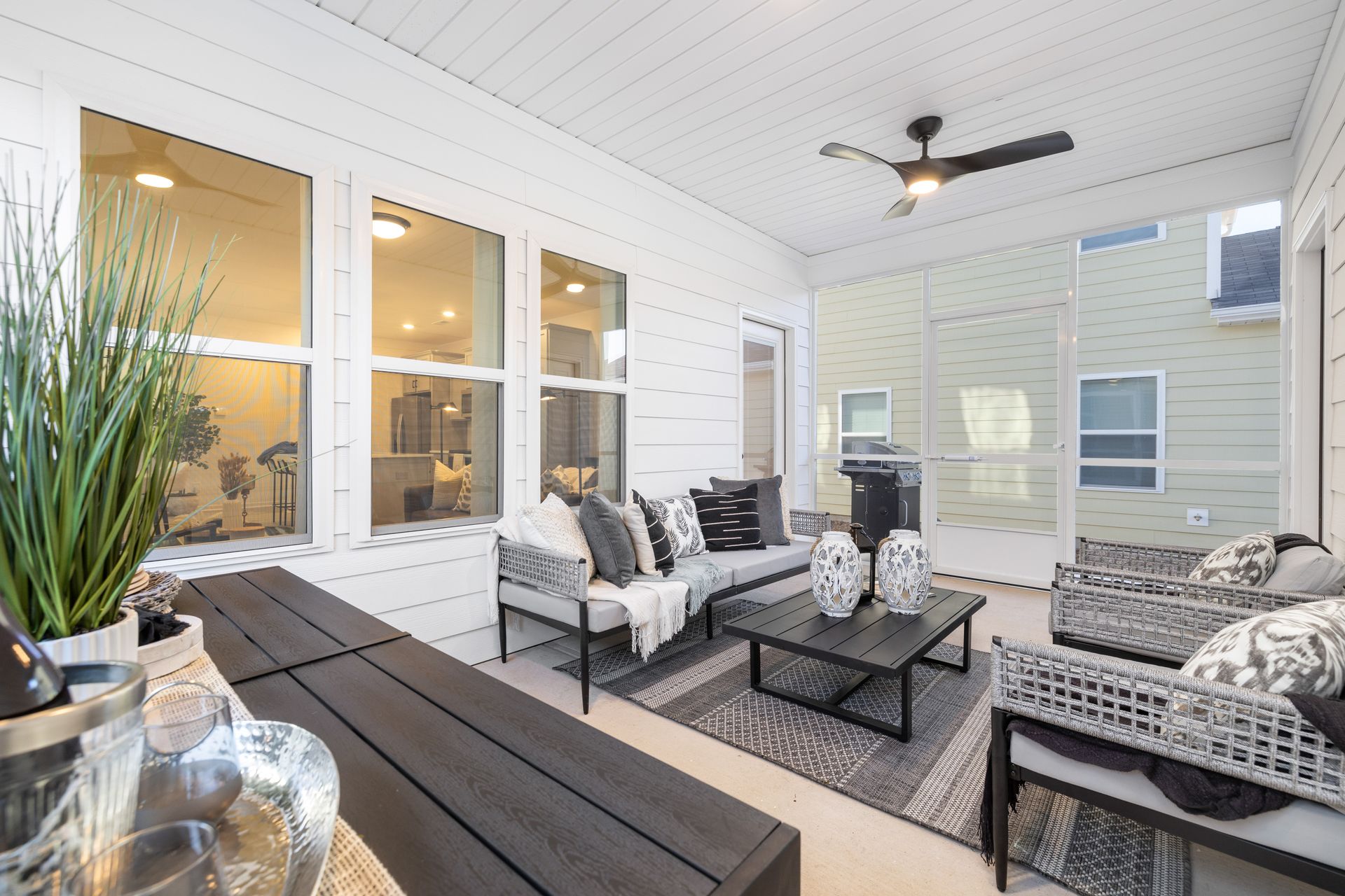 A living room with a couch , chairs , a table and a ceiling fan.