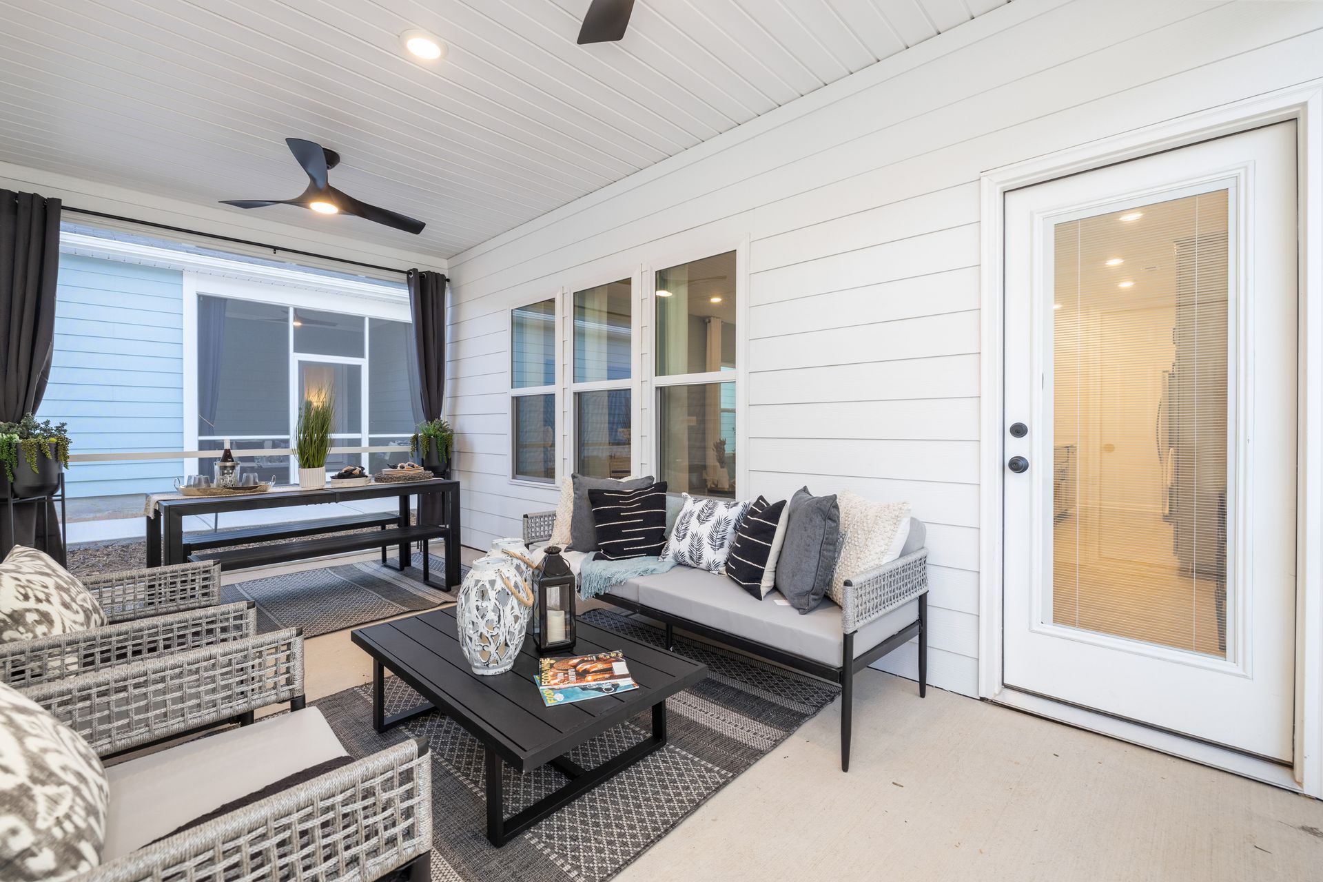 A living room with a couch , chairs , a table and a ceiling fan.
