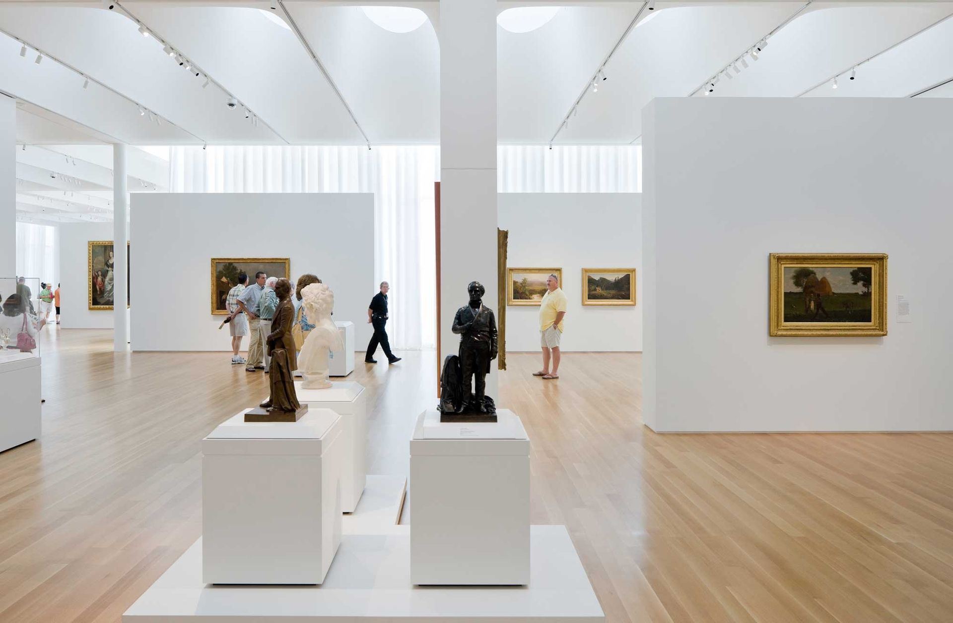 A group of people are looking at sculptures in a museum.