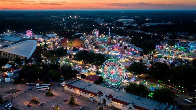 An aerial view of a carnival at night with a ferris wheel.