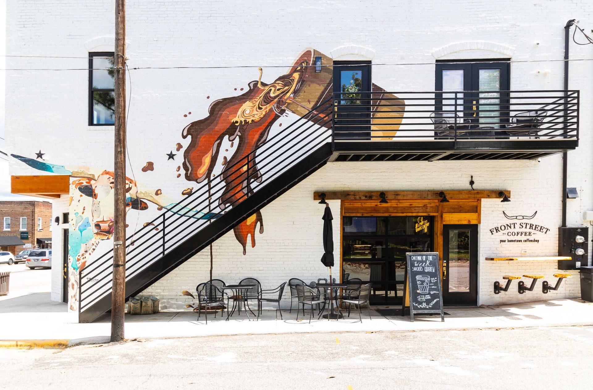 A white building with a staircase and a mural on the side of it.