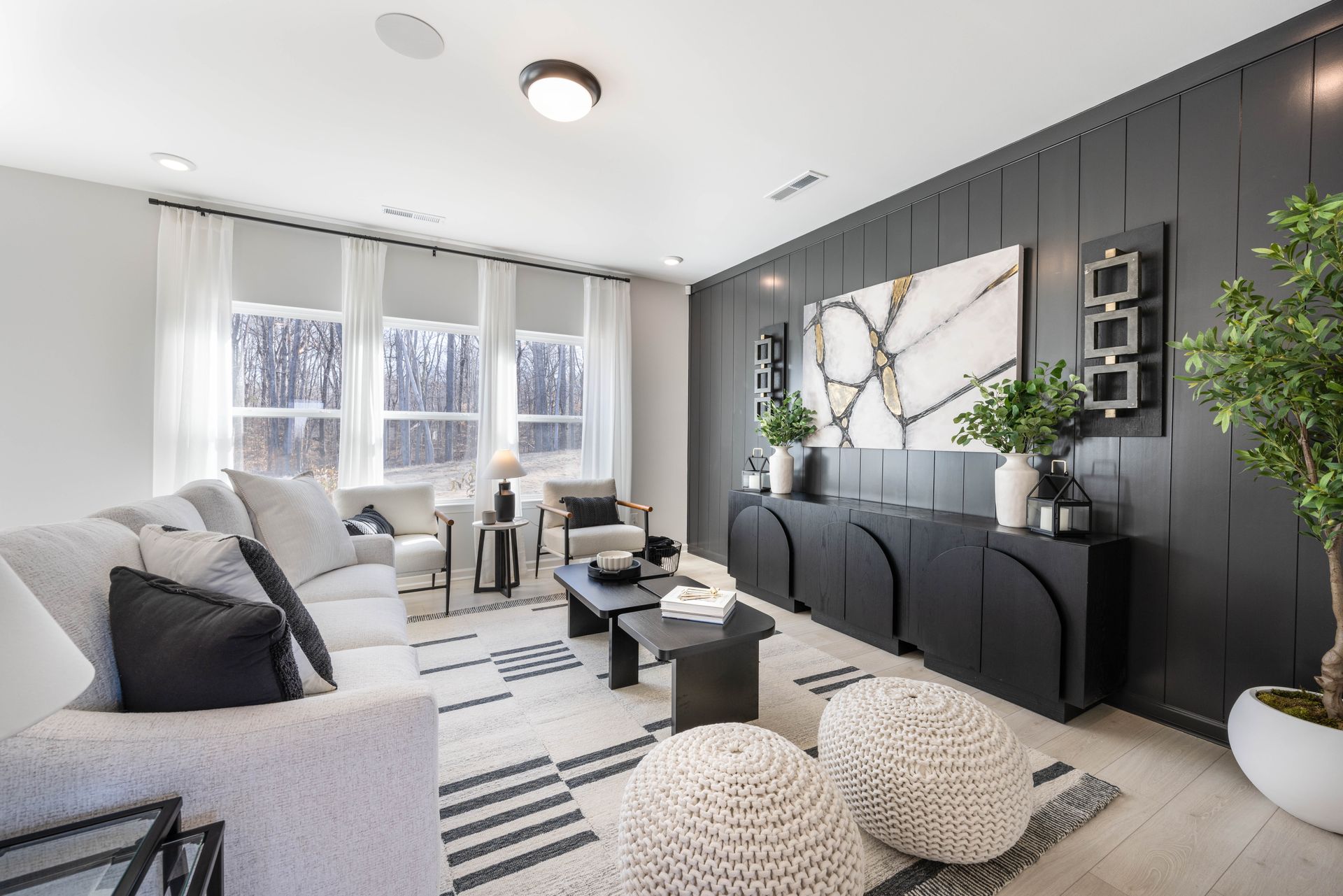 A living room with a couch , chairs , coffee table and ottomans.
