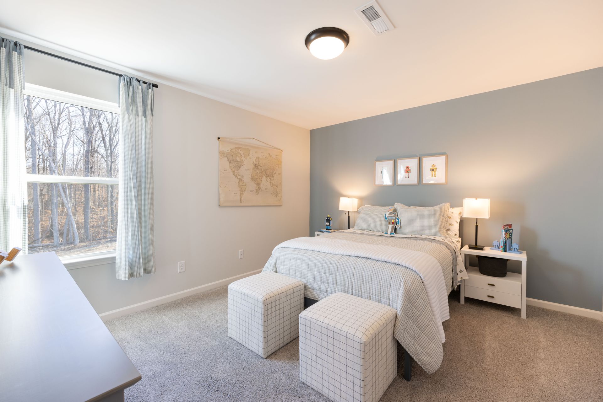 A bedroom with a bed , ottomans , nightstands and a window.