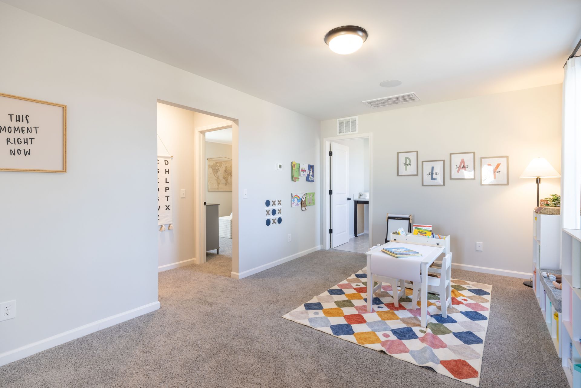A play room with a table and chairs and a colorful rug.