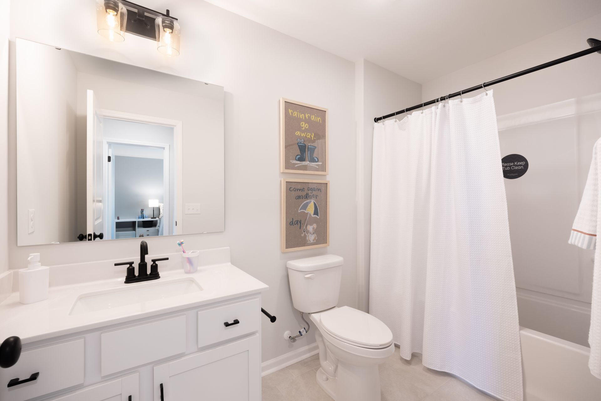 A bathroom with a toilet , sink , mirror and shower curtain.