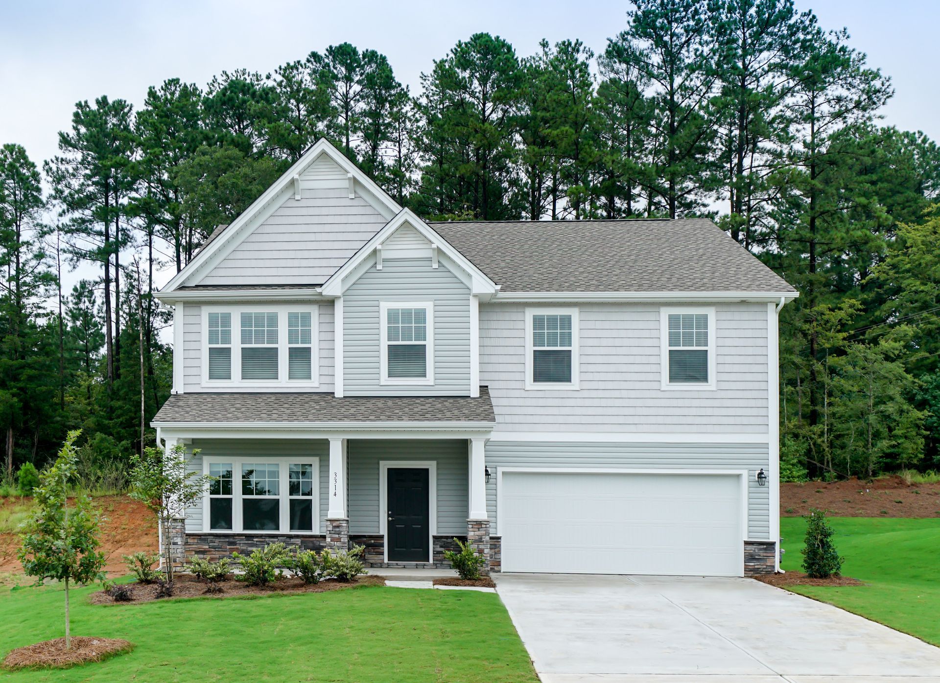 A large white house with a garage and trees in the background