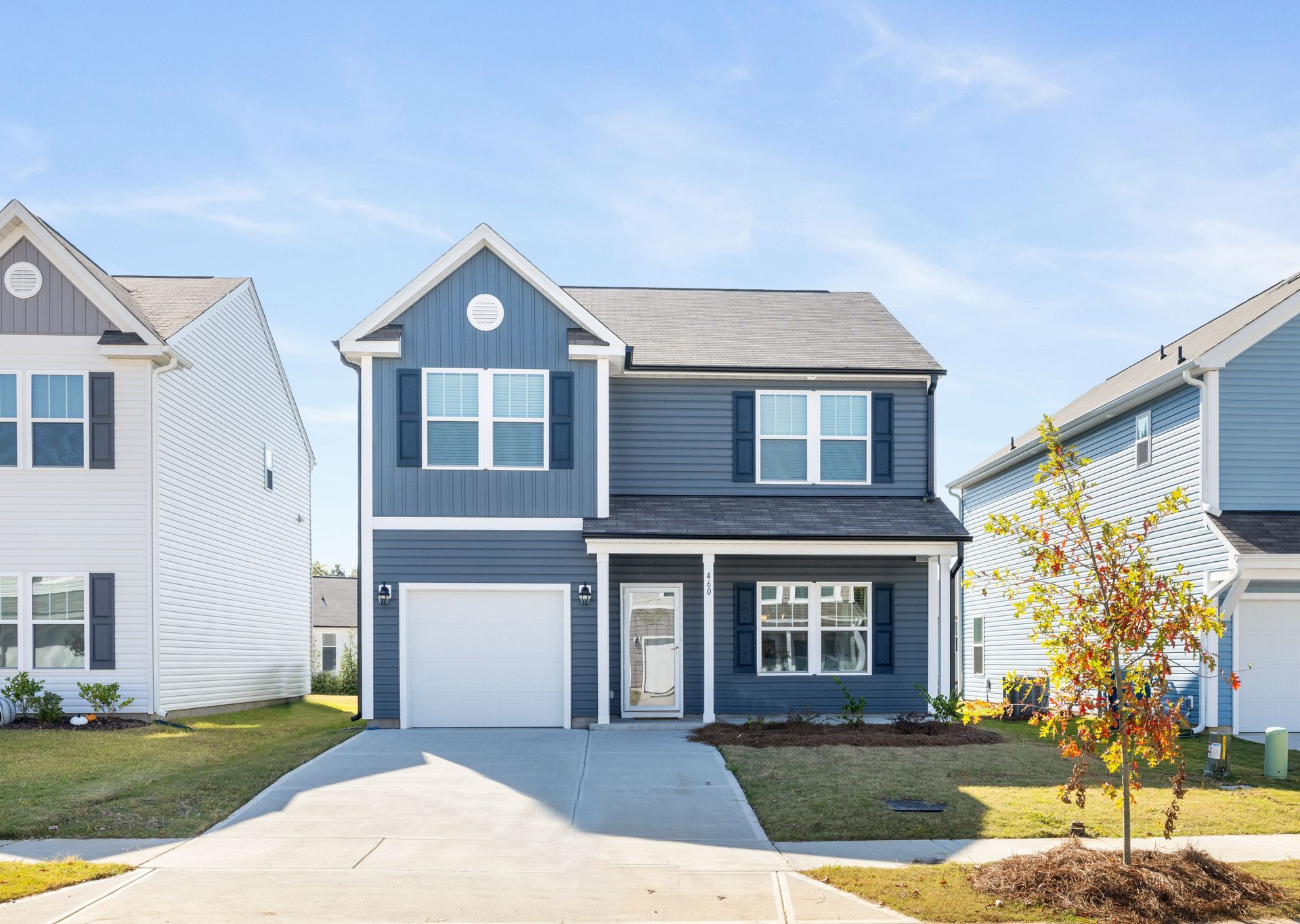 A blue house with white trim and shutters is sitting next to a white house.