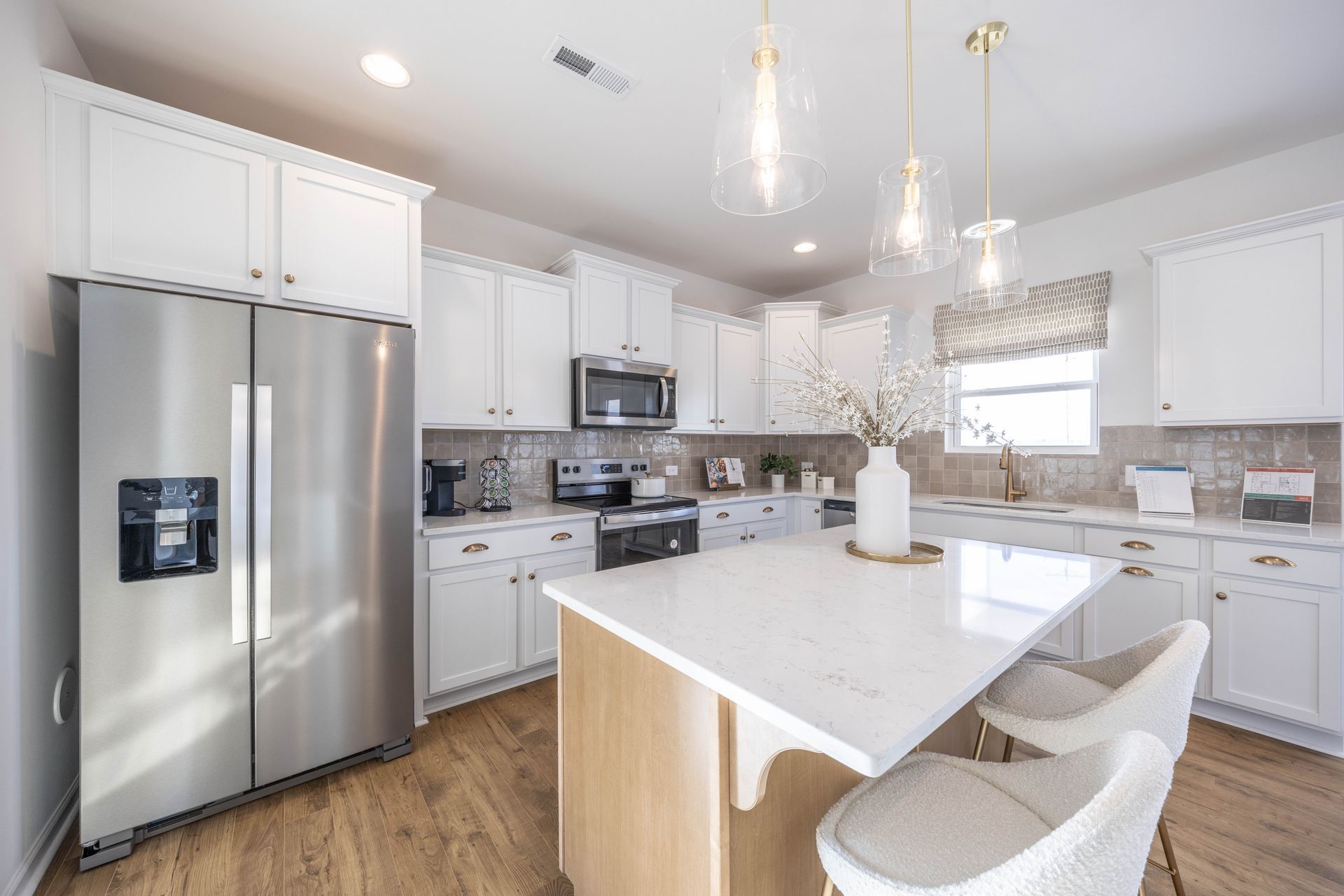 A kitchen with white cabinets , stainless steel appliances , and a large island.