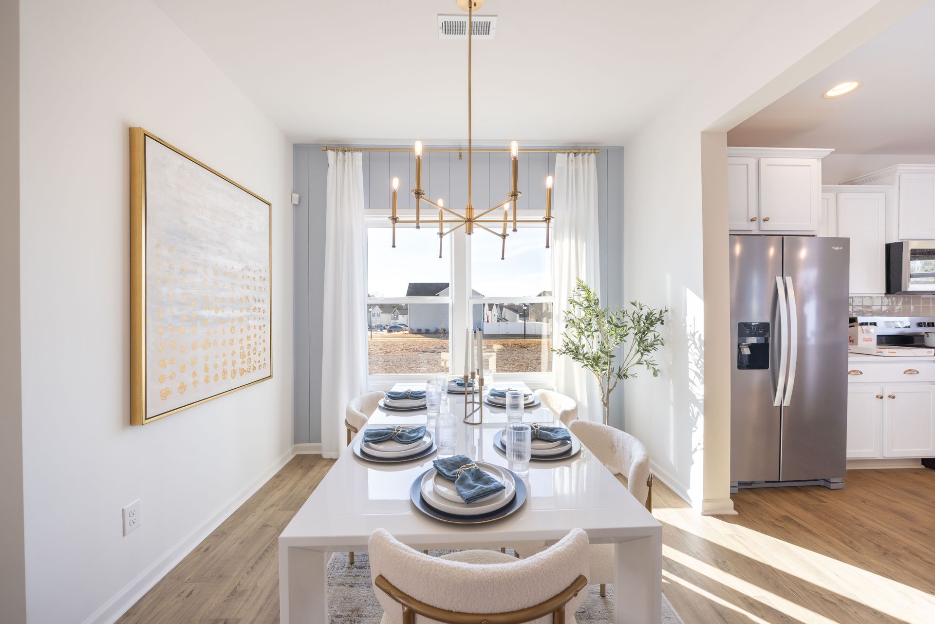 A dining room with a table and chairs and a stainless steel refrigerator.