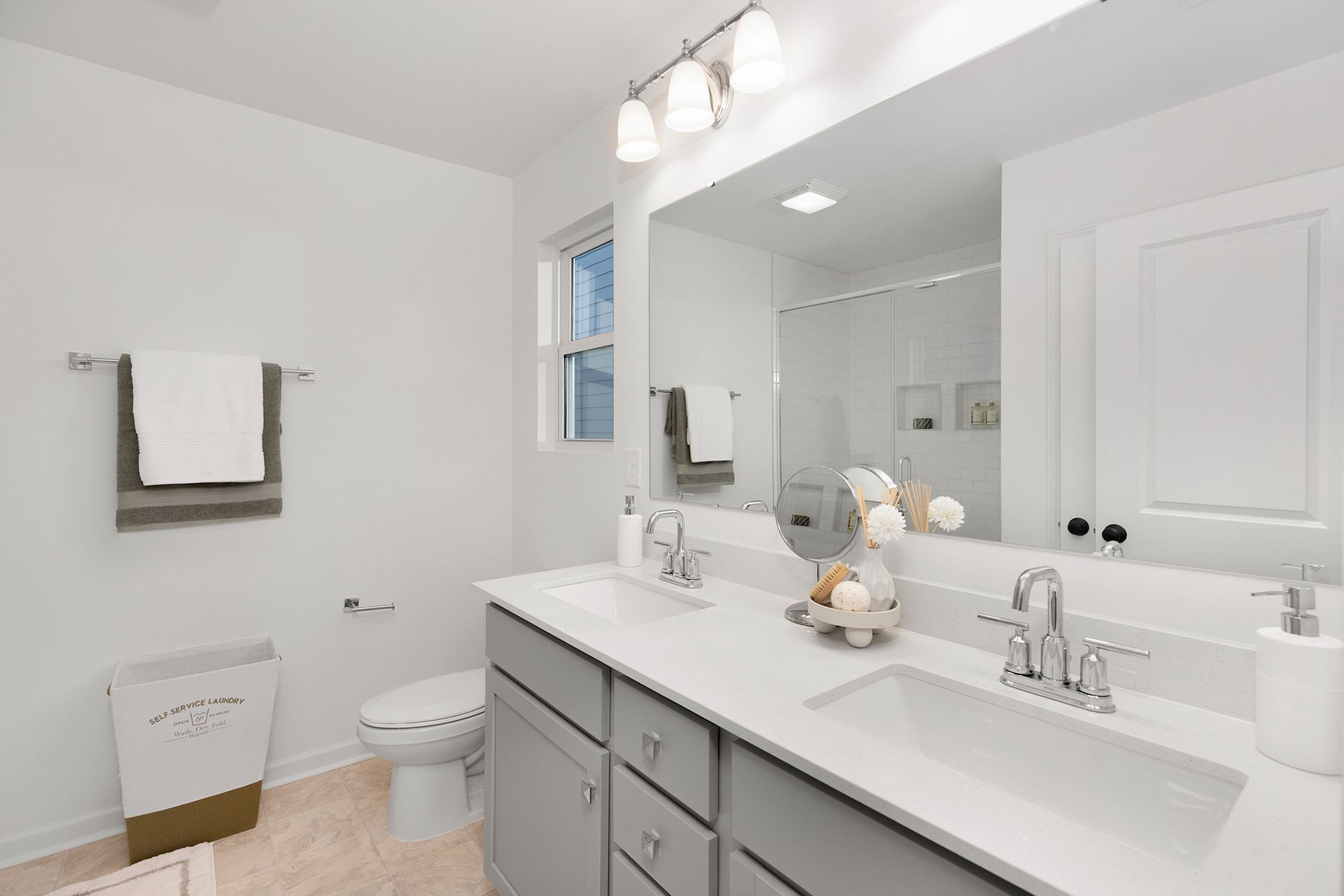 A bathroom with two sinks , a toilet , and a large mirror.