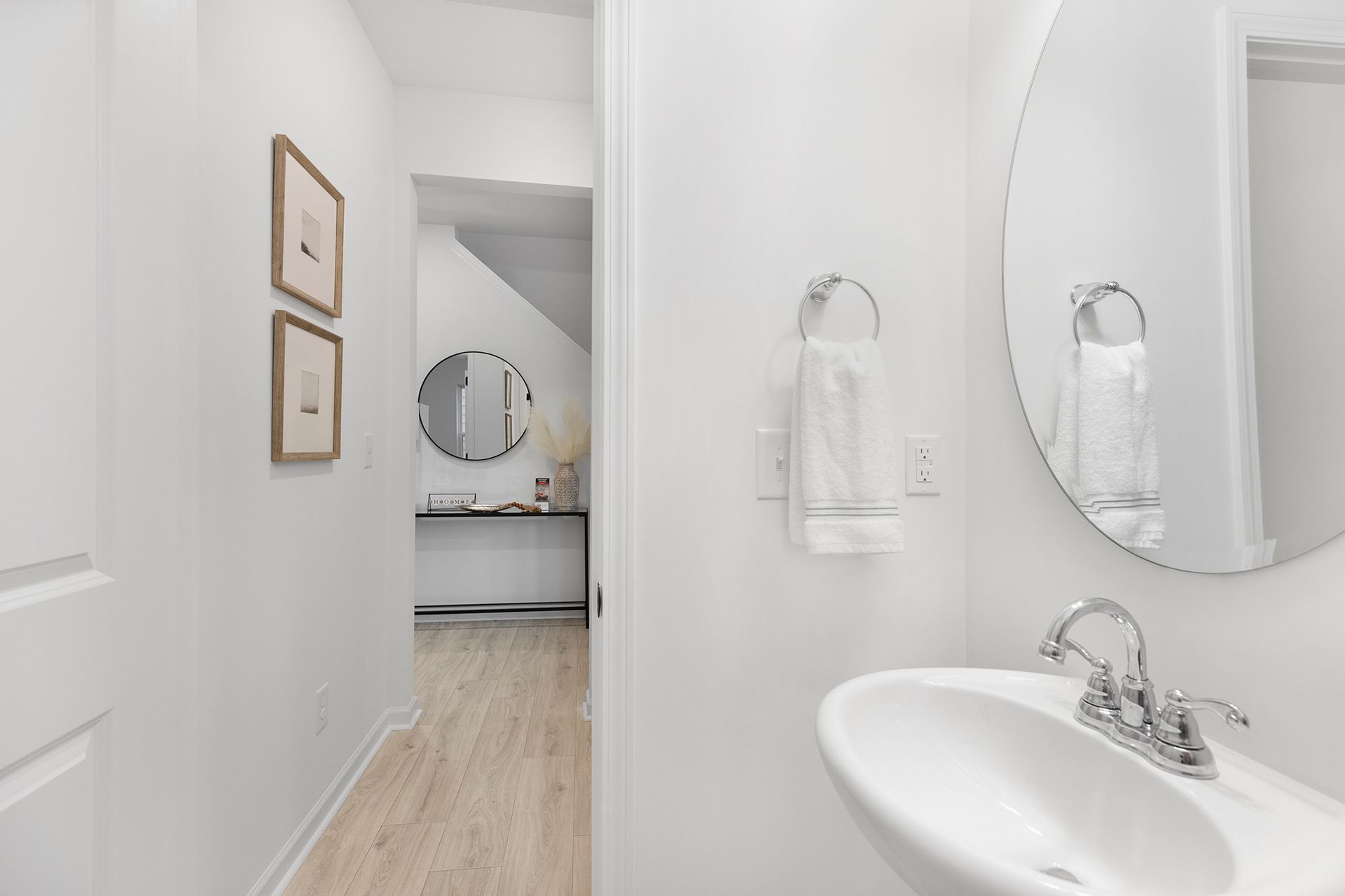 A bathroom with a sink , mirror and towels hanging on the wall.