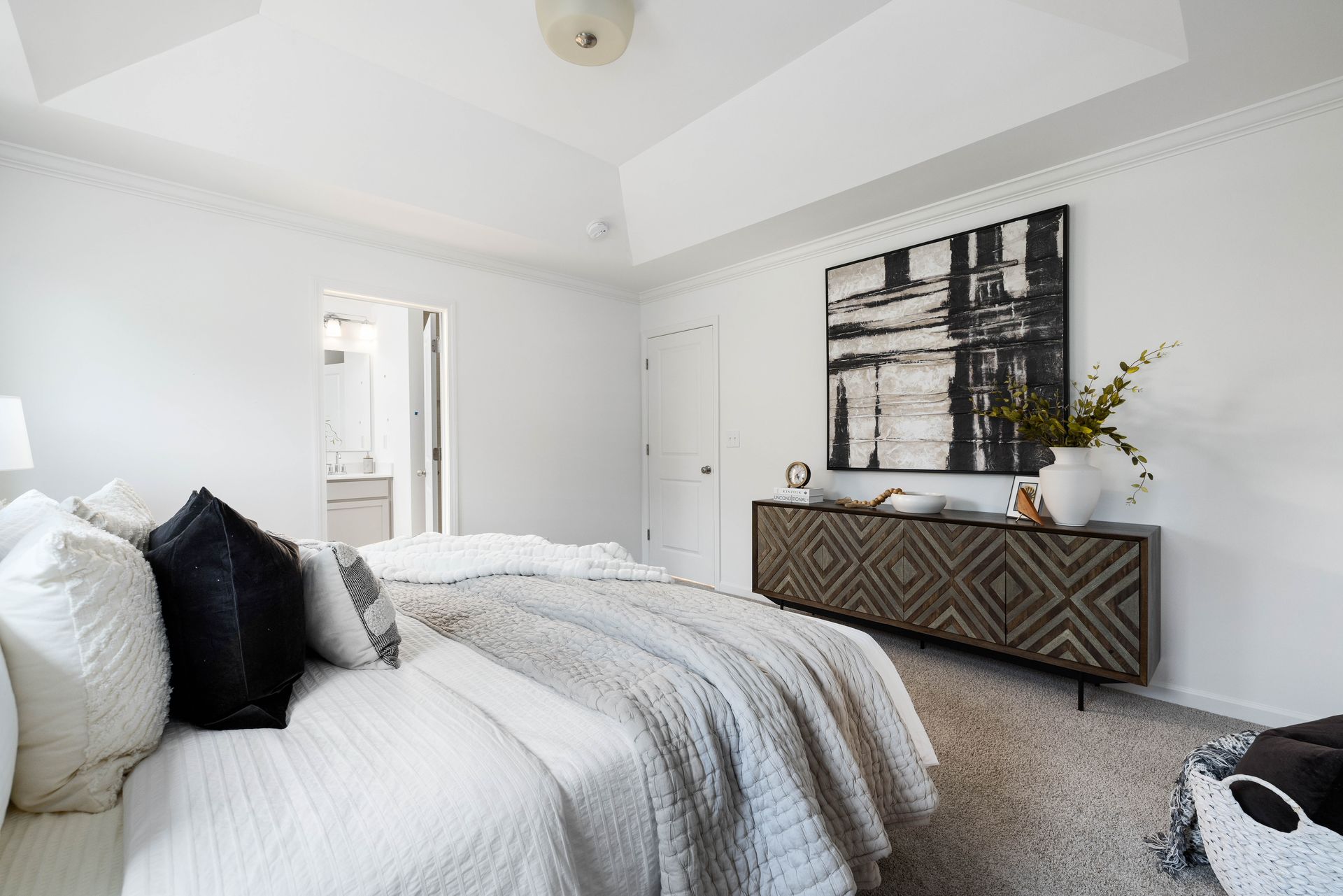 A bedroom with a large bed , dresser , and painting on the wall.