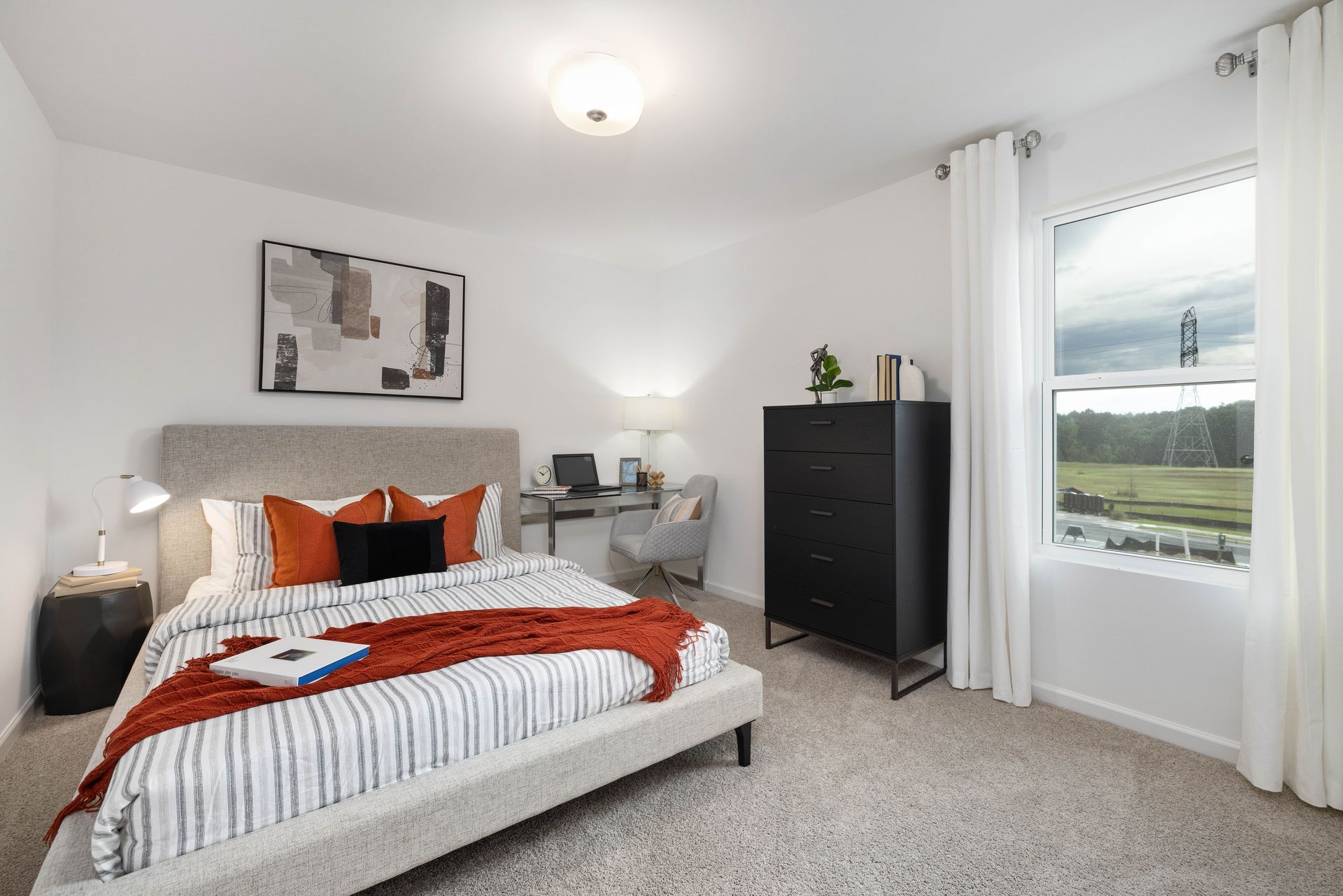 A bedroom with a bed , dresser , desk and window.