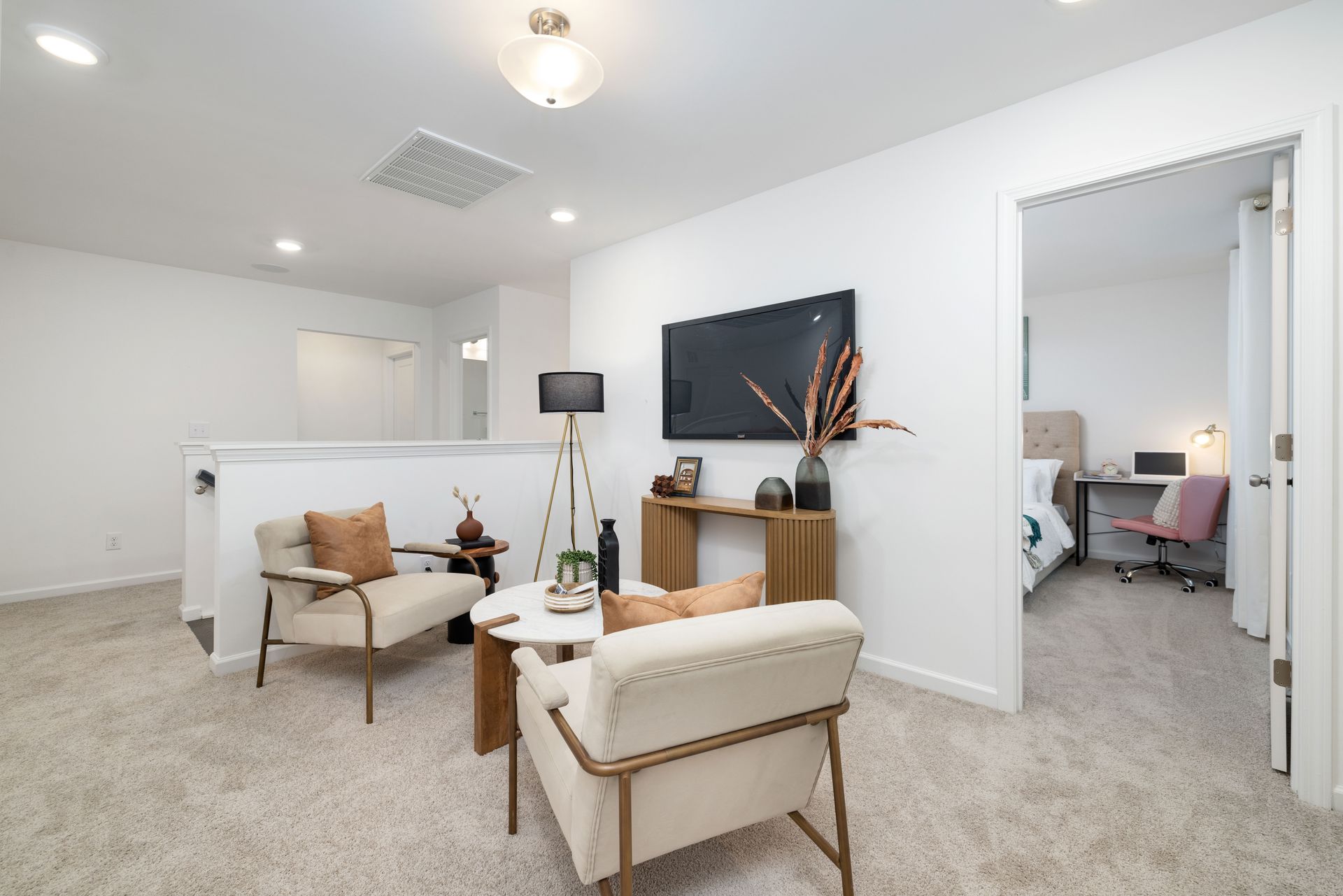 A living room with two chairs and a television on the wall.