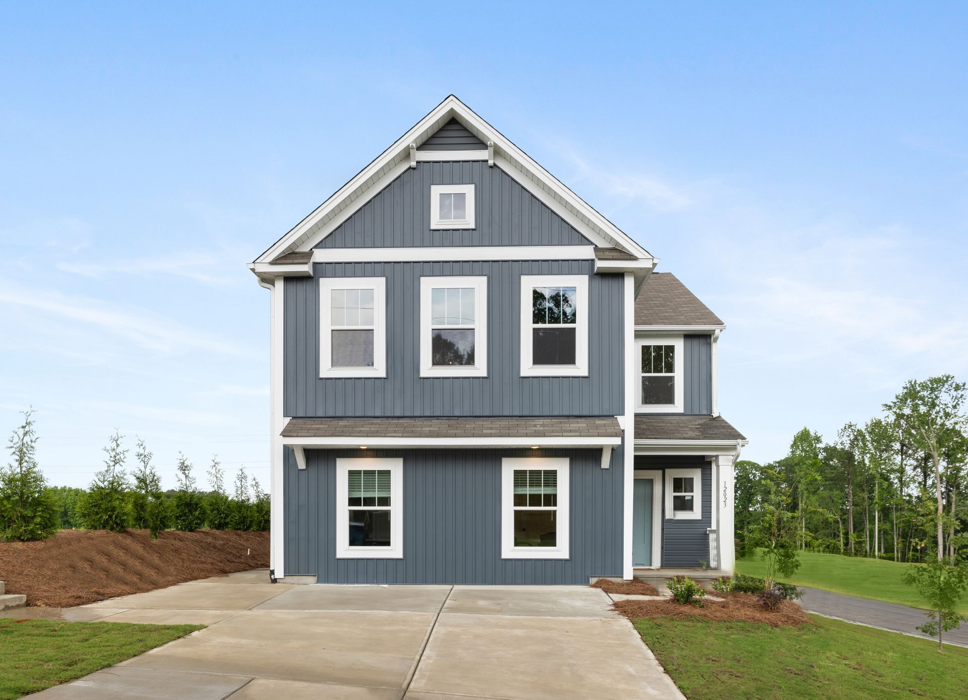 The front of a blue house with white trim and windows.