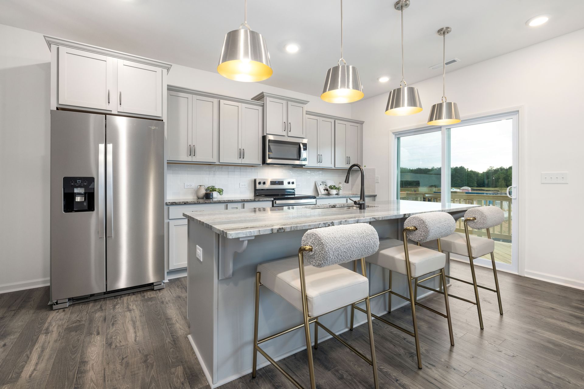 A kitchen with stainless steel appliances , white cabinets , and a large island.
