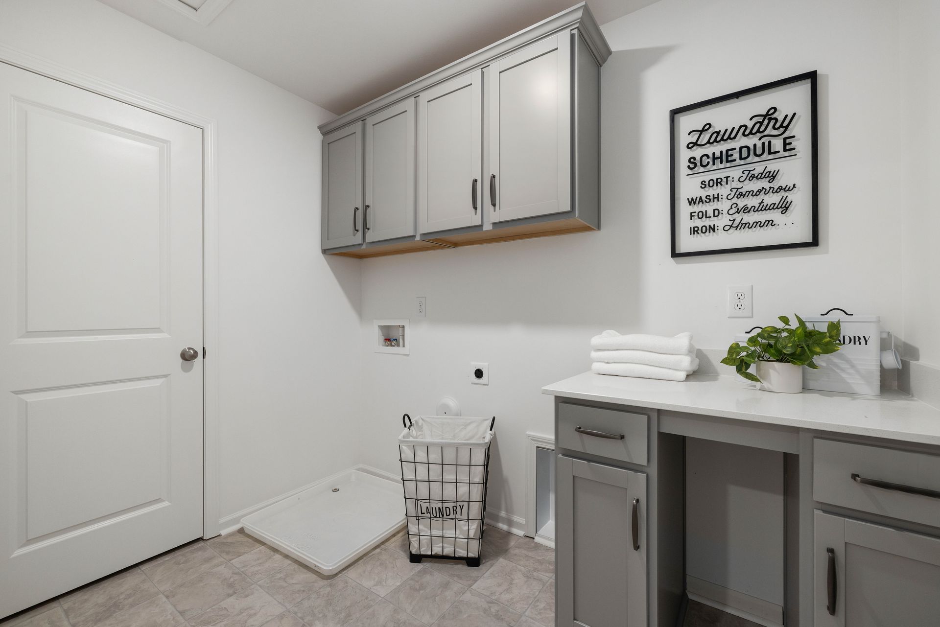 A laundry room with a sink , cabinets , and a sign on the wall.