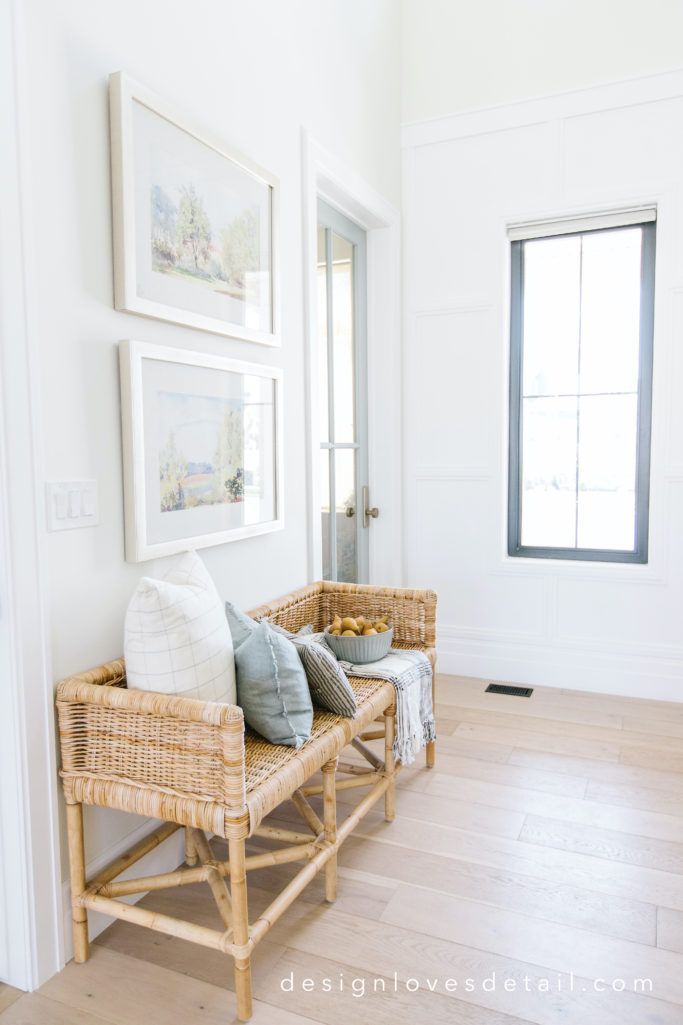 A wicker bench is sitting in a hallway next to a window.